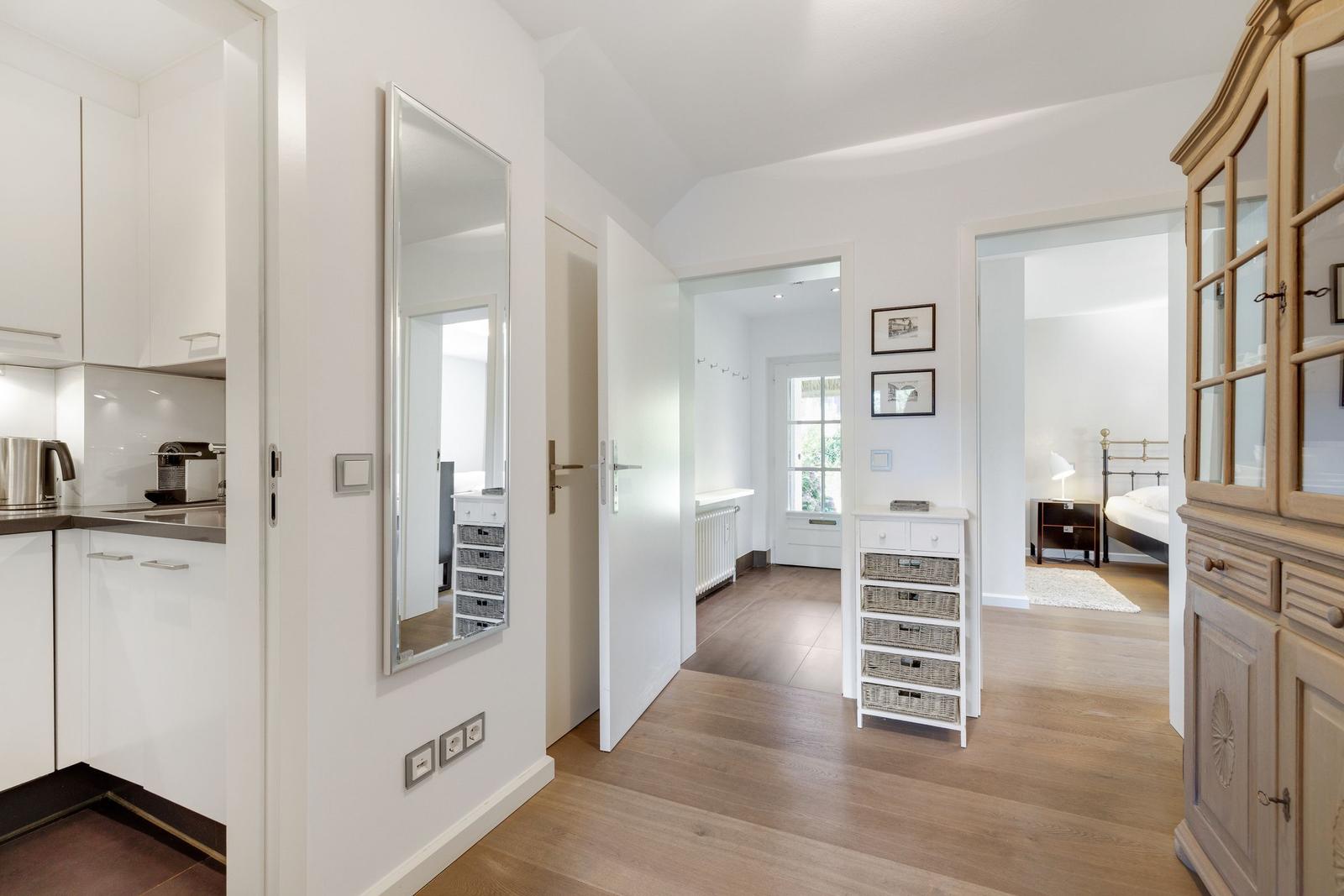 Hallway with kitchen area, mirror, and view into bedroom and living area.