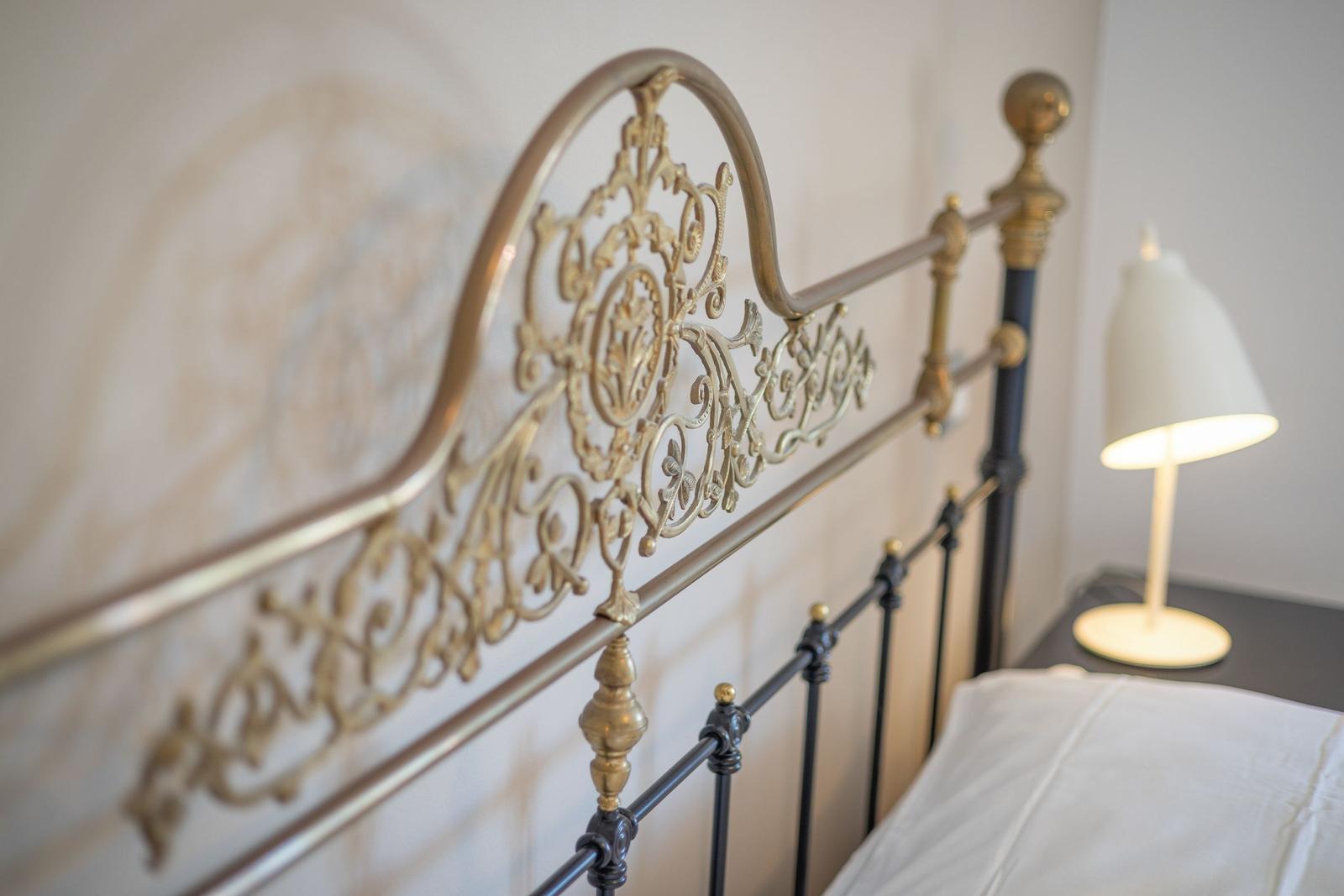 Bedroom with ornate metal bed and bedside lamp.