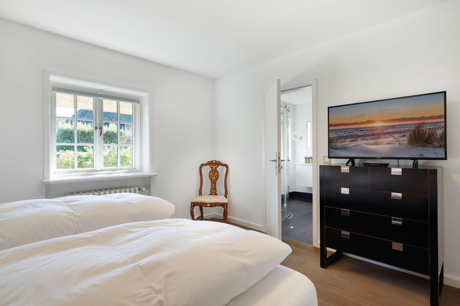 Bedroom with double bed, TV, and view of garden.