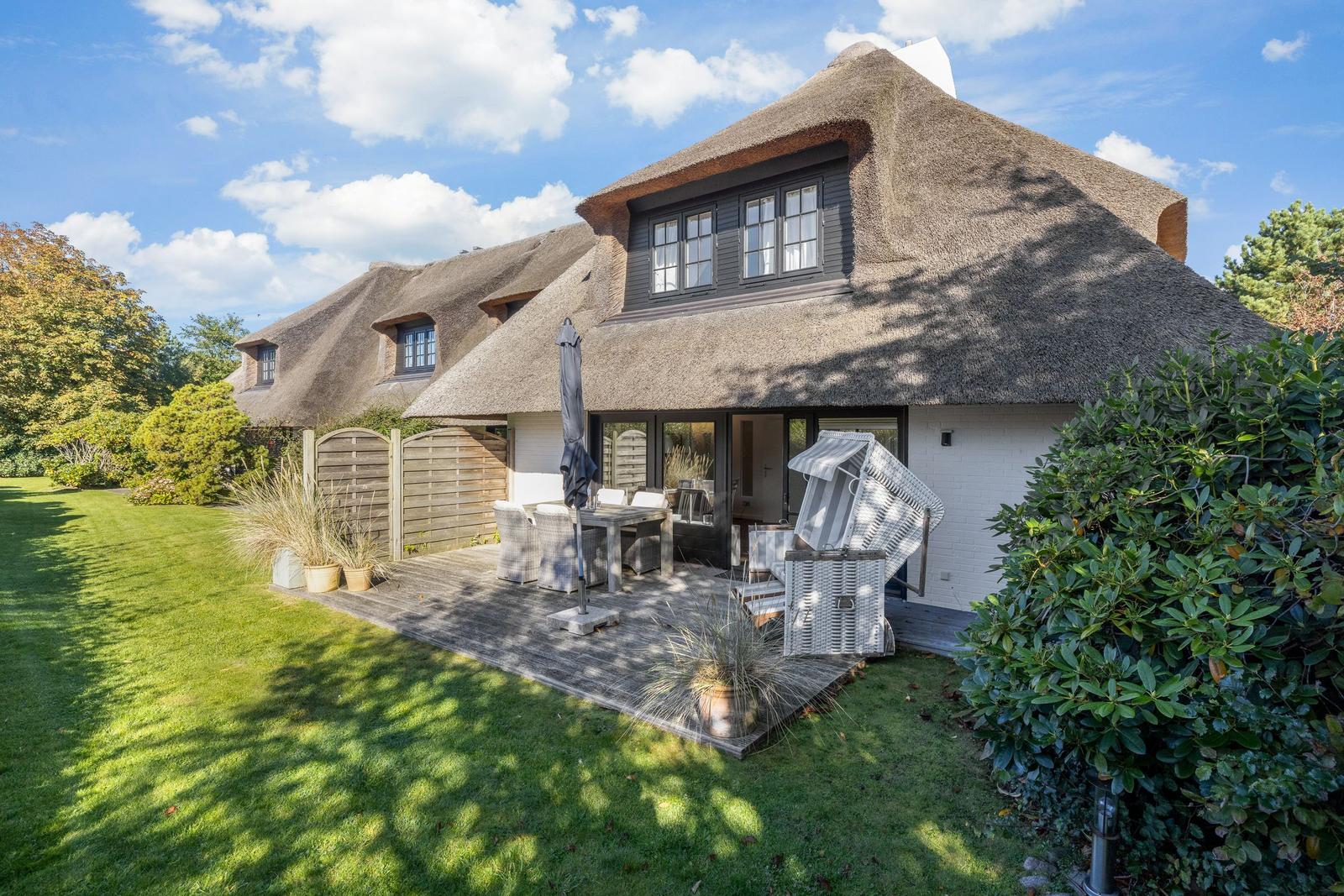 House with thatched roof, terrace and garden. Furnished outdoor terrace with table and chairs.
