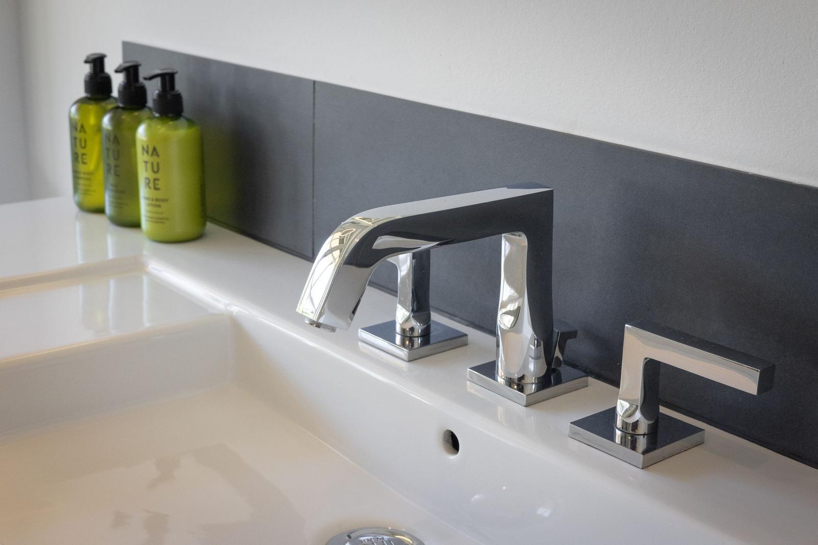 Sink with modern faucet and green bottles.