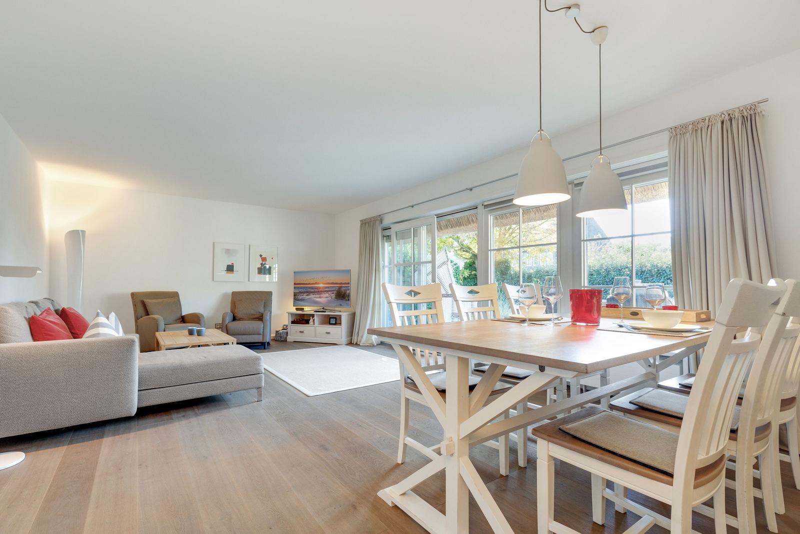 Dining area with table and chairs next to a living room with sofa and TV.