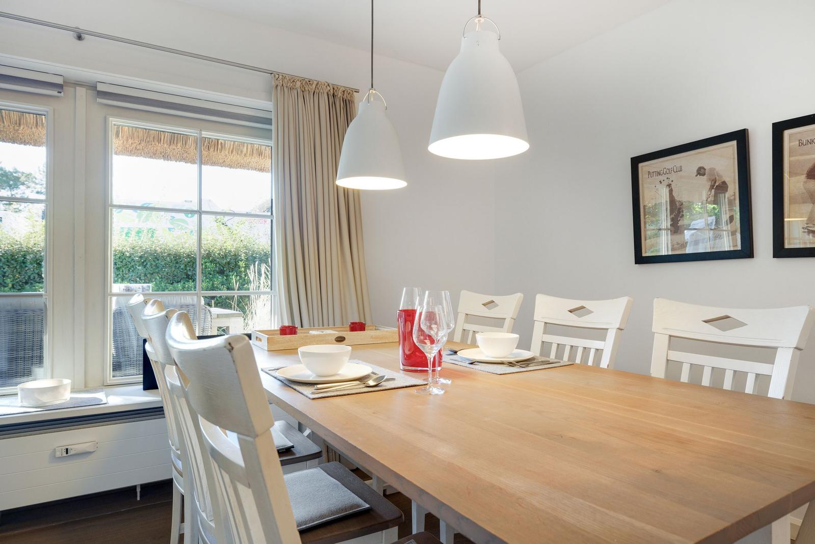 Dining table with chairs, windows, and pendant lamps