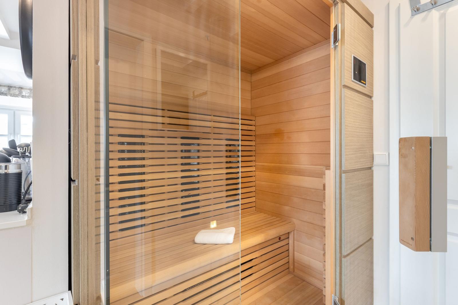 Sauna with wooden walls and bench, door with glass and wooden frame