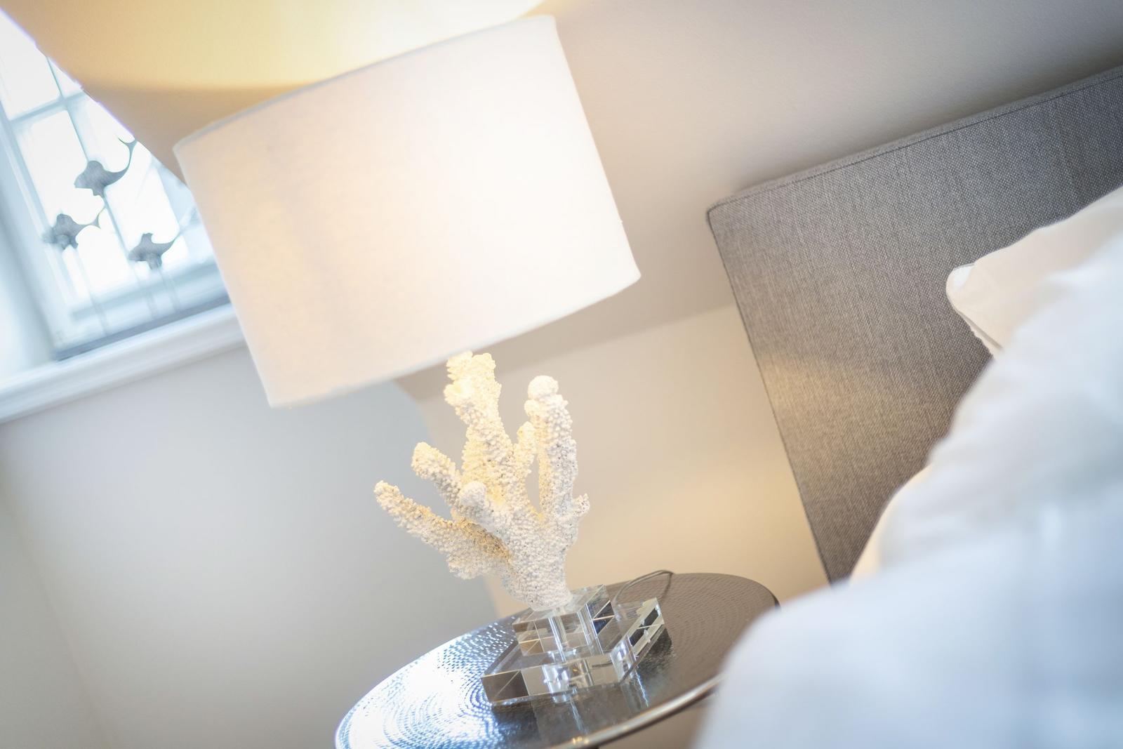 Bedroom with nightstand, lamp, and coral decor.