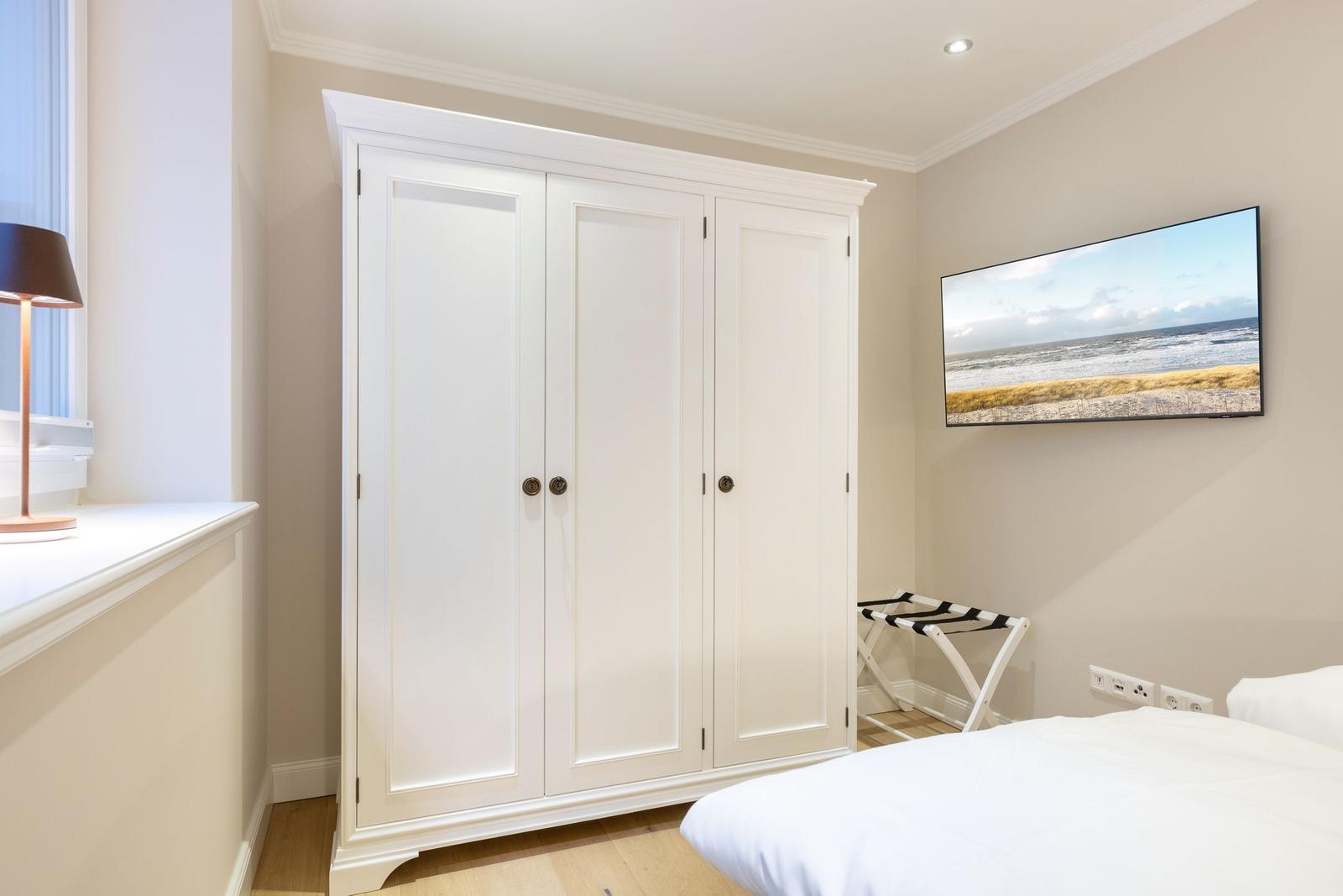 Bedroom with white wardrobe, bed, and wall picture