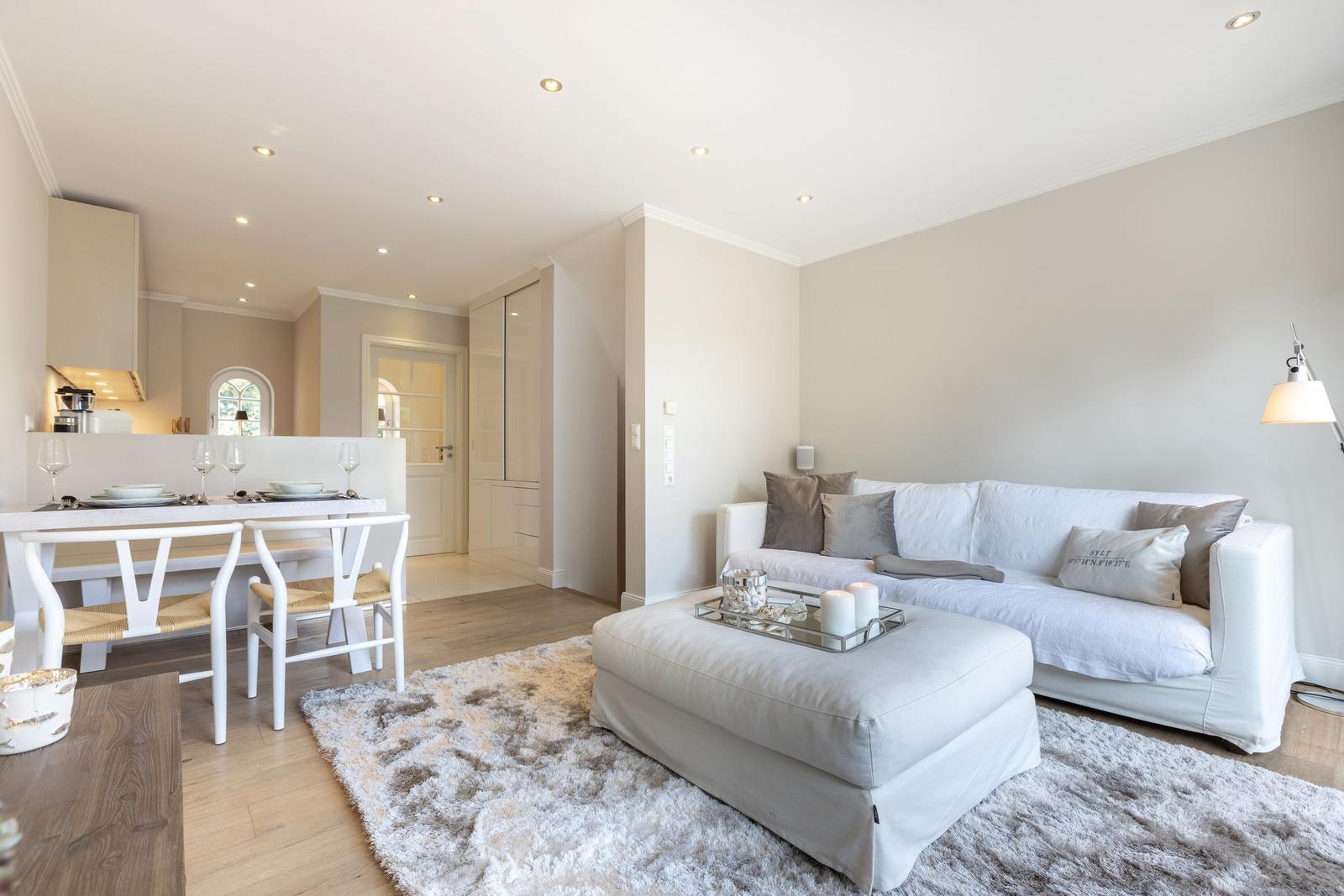 Living and dining area with white sofa, coffee table, and dining table with chairs.