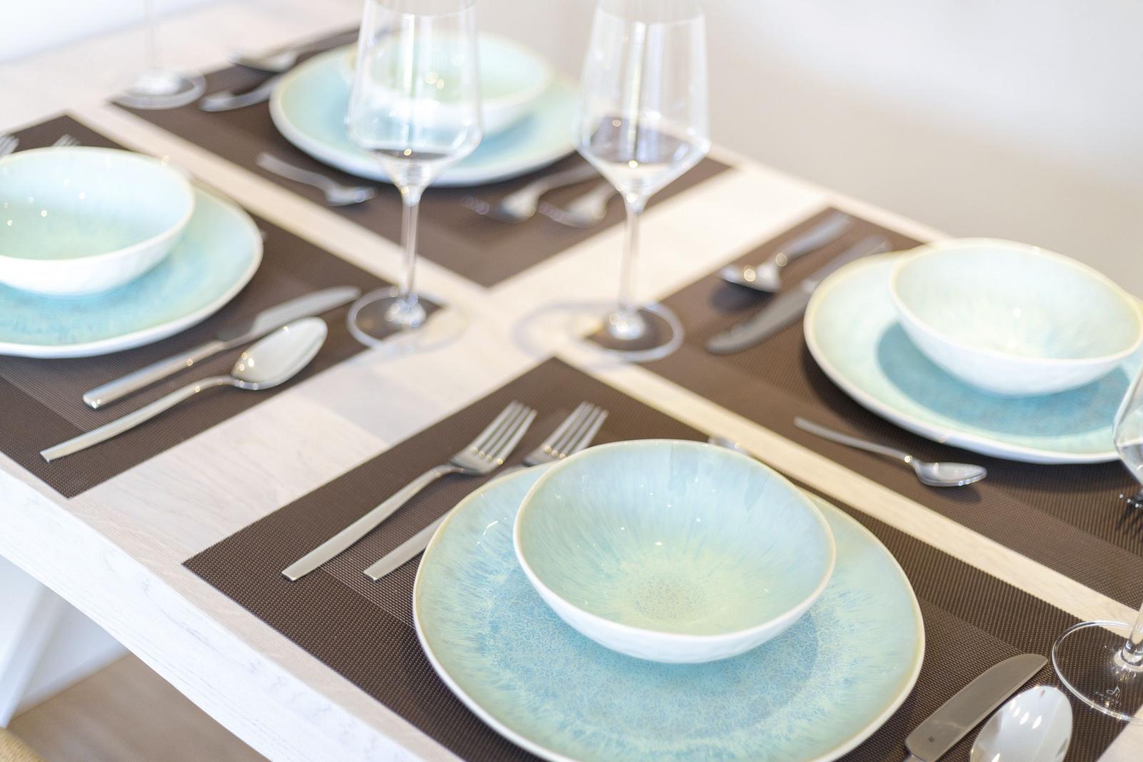 Table set with plates, bowls, and glasses on placemats.