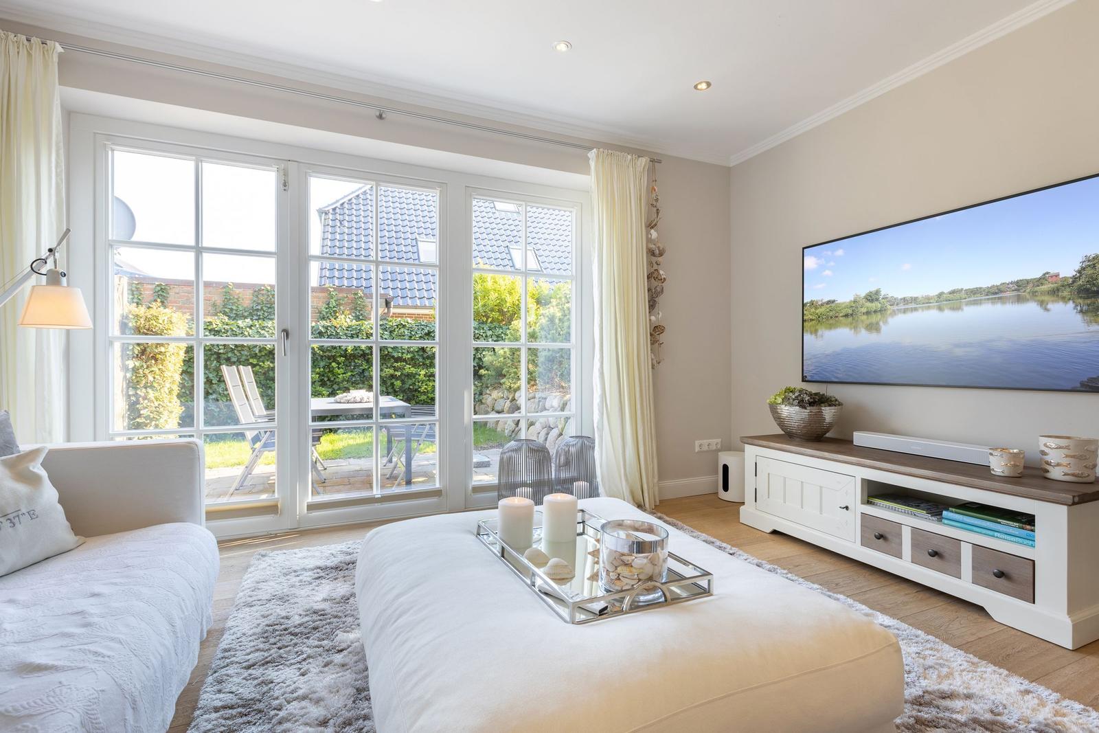 Living room with TV, sofa, and view of garden.