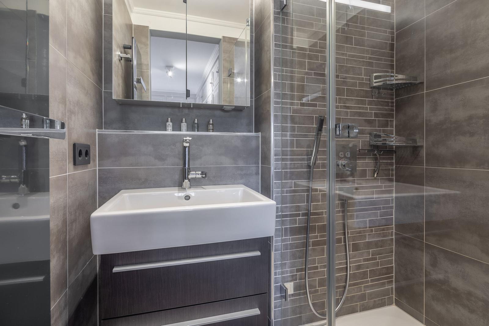 Bad mit Dusche, Waschbecken und Spiegelschrank.