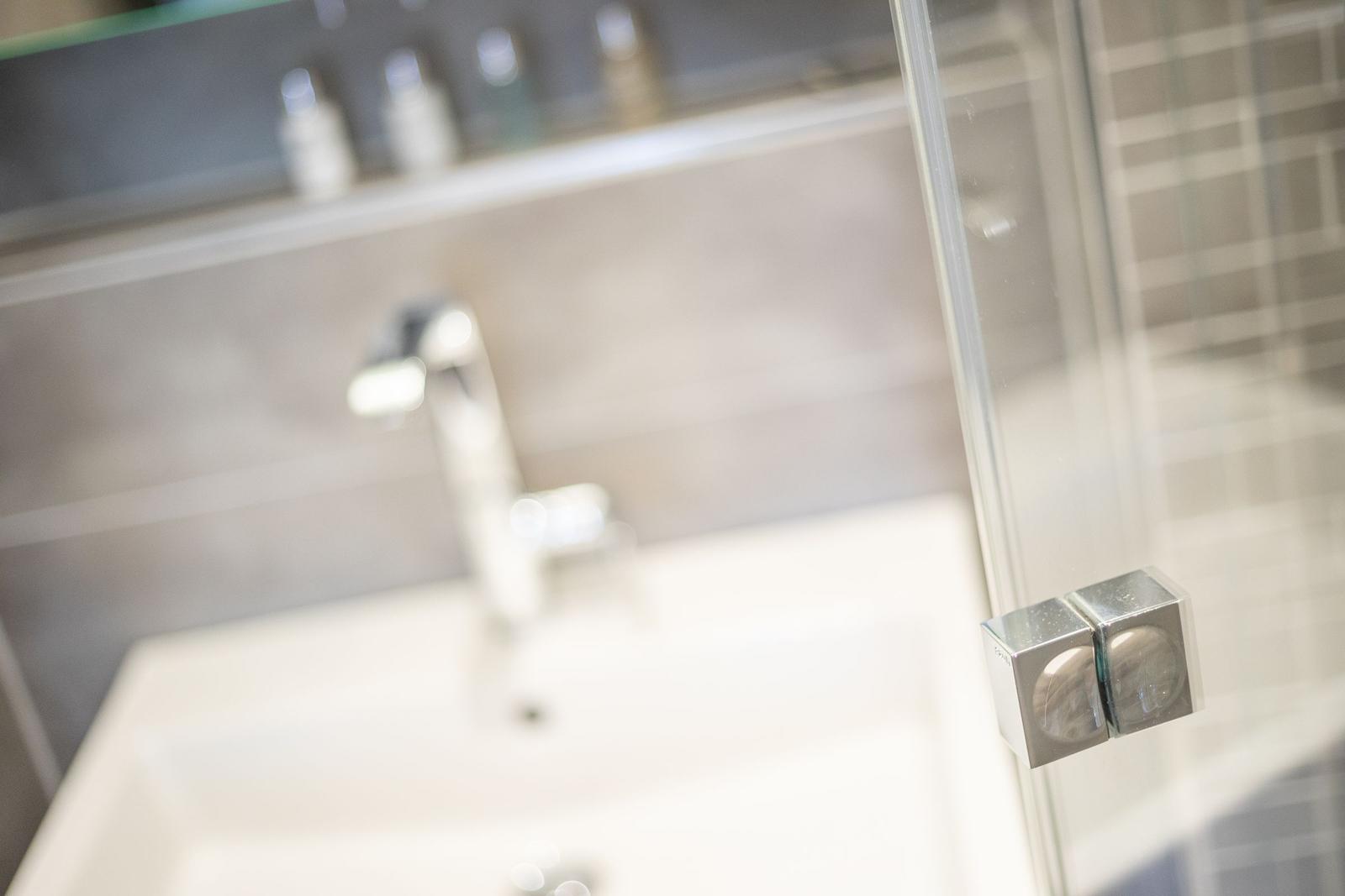 Bad mit Waschbecken und Dusche mit Glaswand