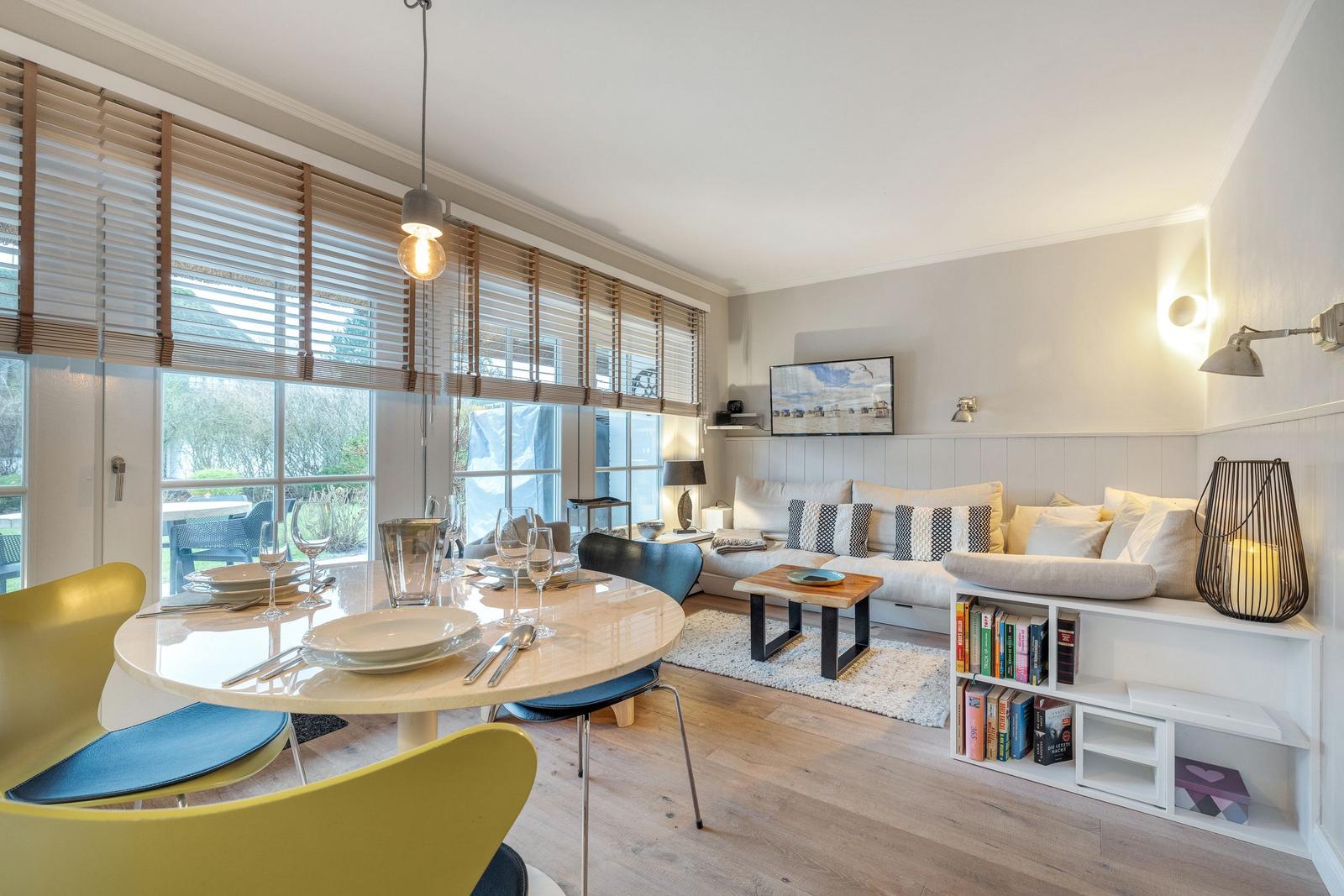 Essbereich mit runder Tafel und Sitzgelegenheiten. Wohnbereich mit Sofa, Couchtisch und Bücherregal.