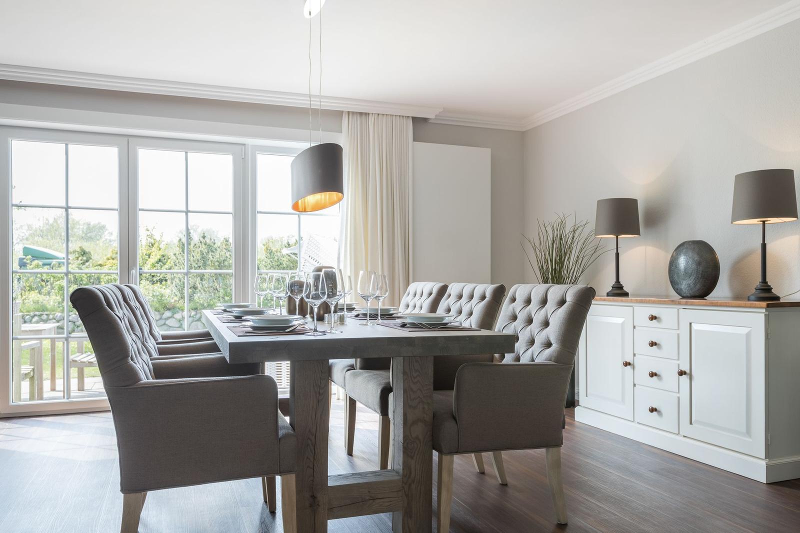 Esszimmer mit Tisch, Stühlen und Blick auf Garten.