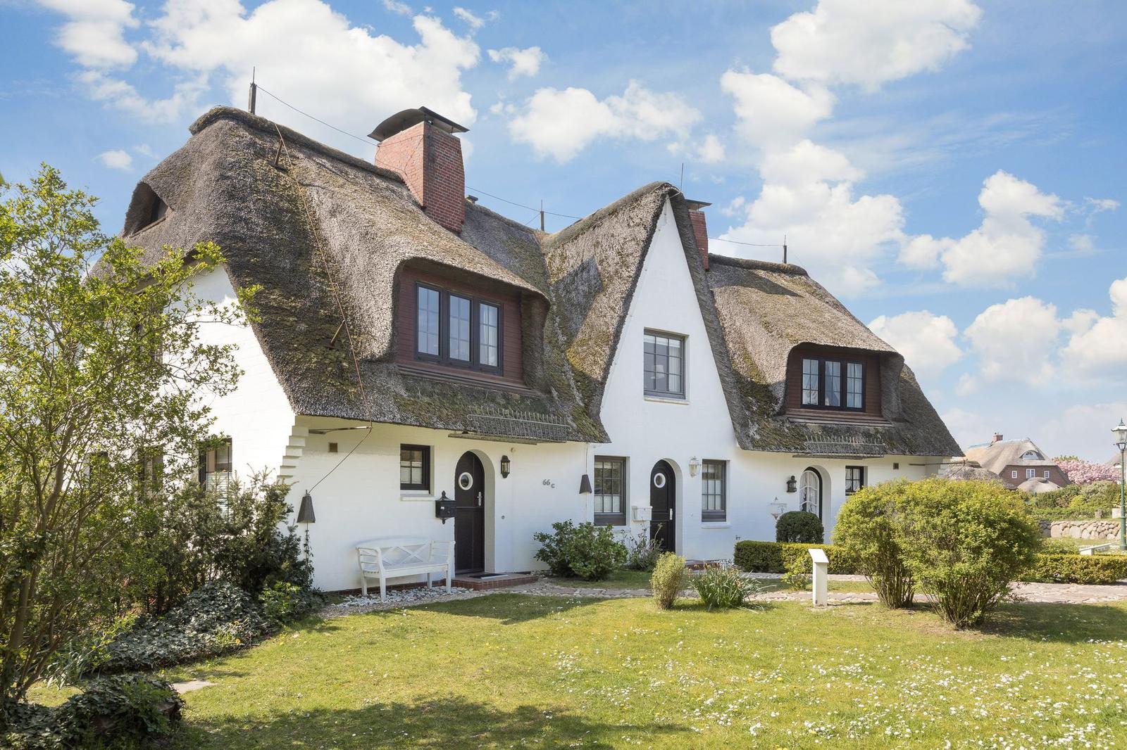 Wohnhaus mit Strohdach, weißen Wänden und Garten