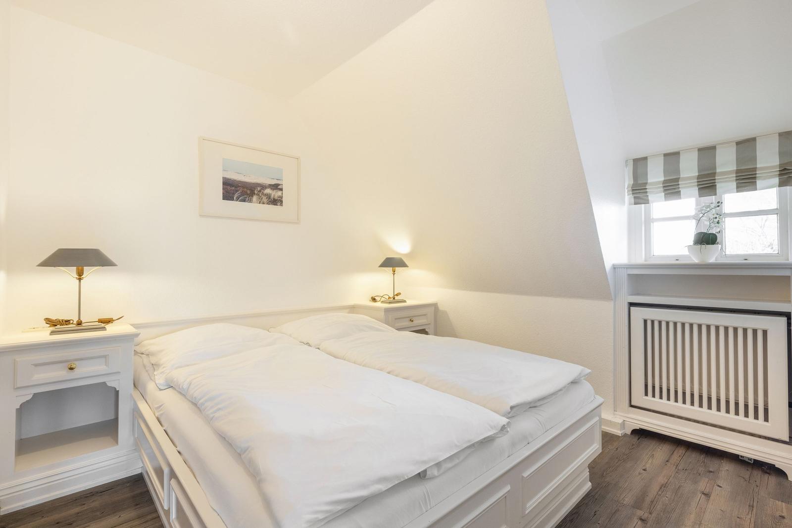 Bedroom with double bed, two nightstands, and window with awnings.
