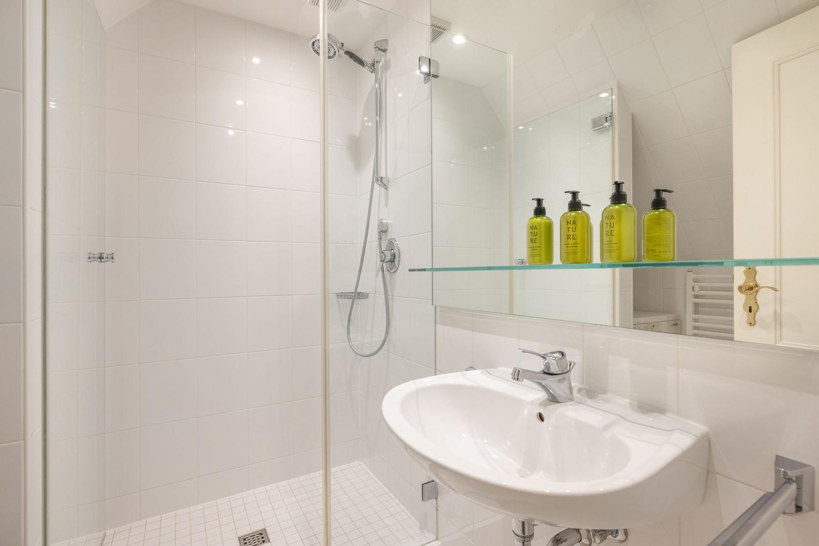 Bathroom with shower, sink, and mirror cabinet with bottles.