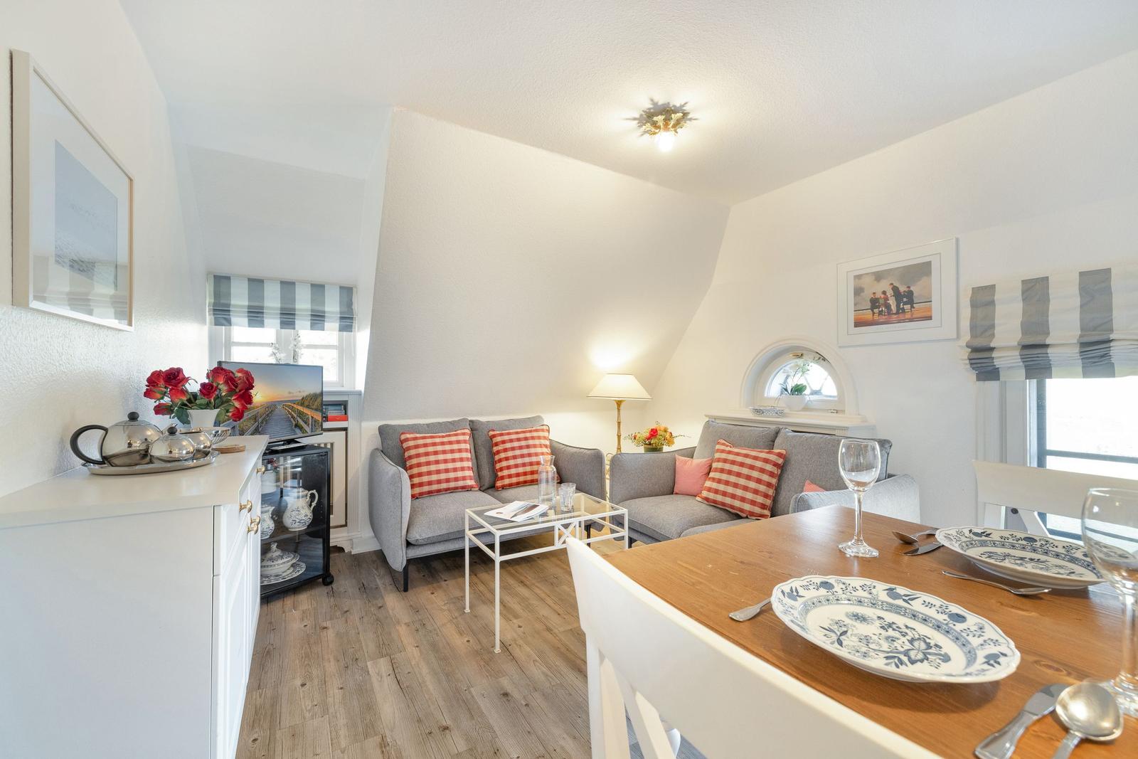 Living and dining area with sofa, table, and windows.