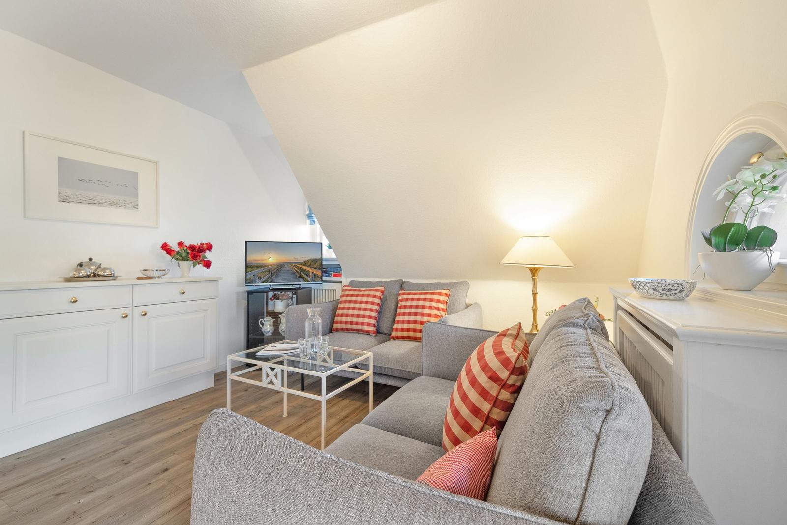 Living room with sofa, coffee table, and TV under sloped ceiling.