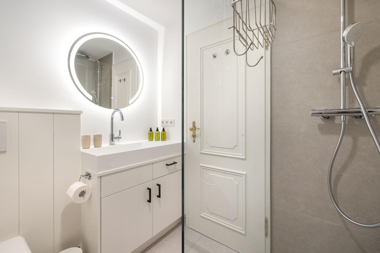 Badezimmer mit Dusche, Waschbecken und Spiegel
