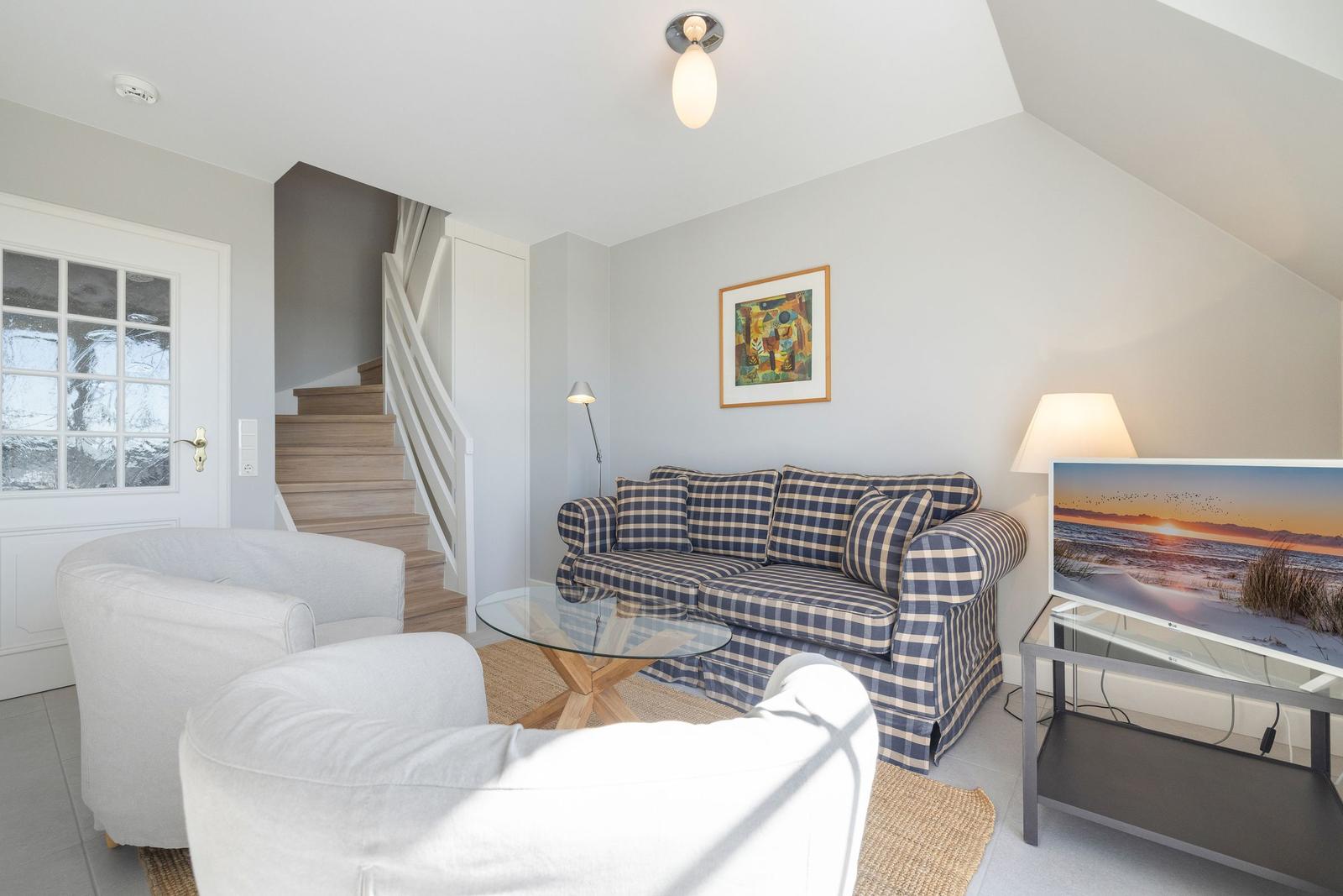 Wohnzimmer mit Sofa, Sessel, Glas-Tisch und Fernseher