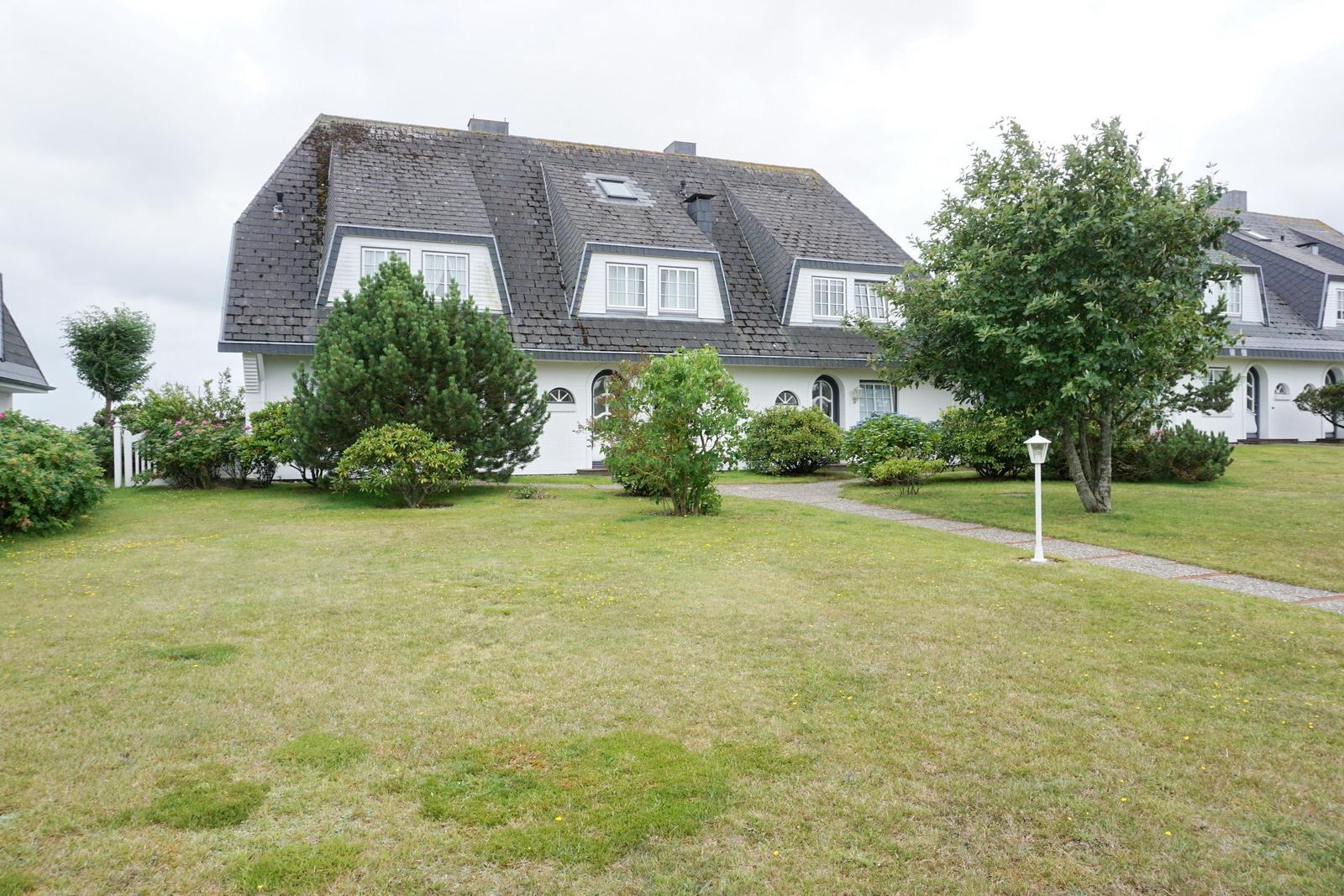 White house with gray roof and green garden.