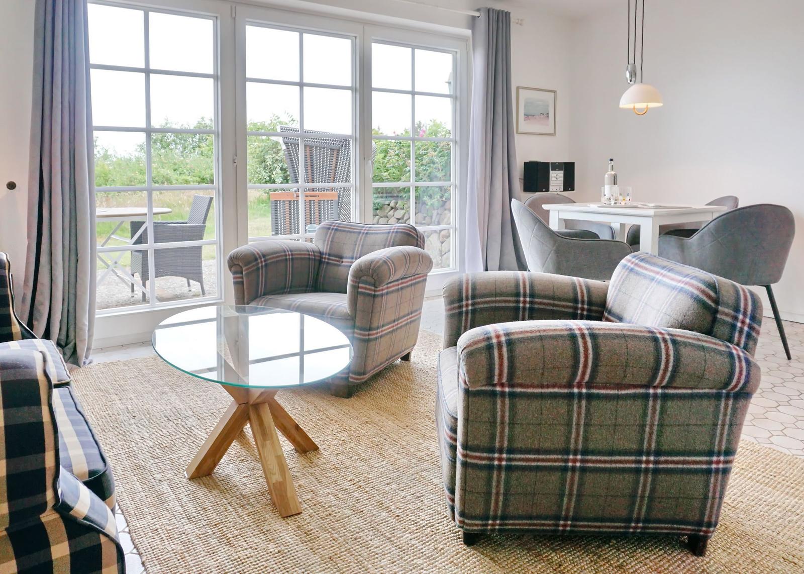 Living room with two patterned armchairs, glass table, and view of terrace.