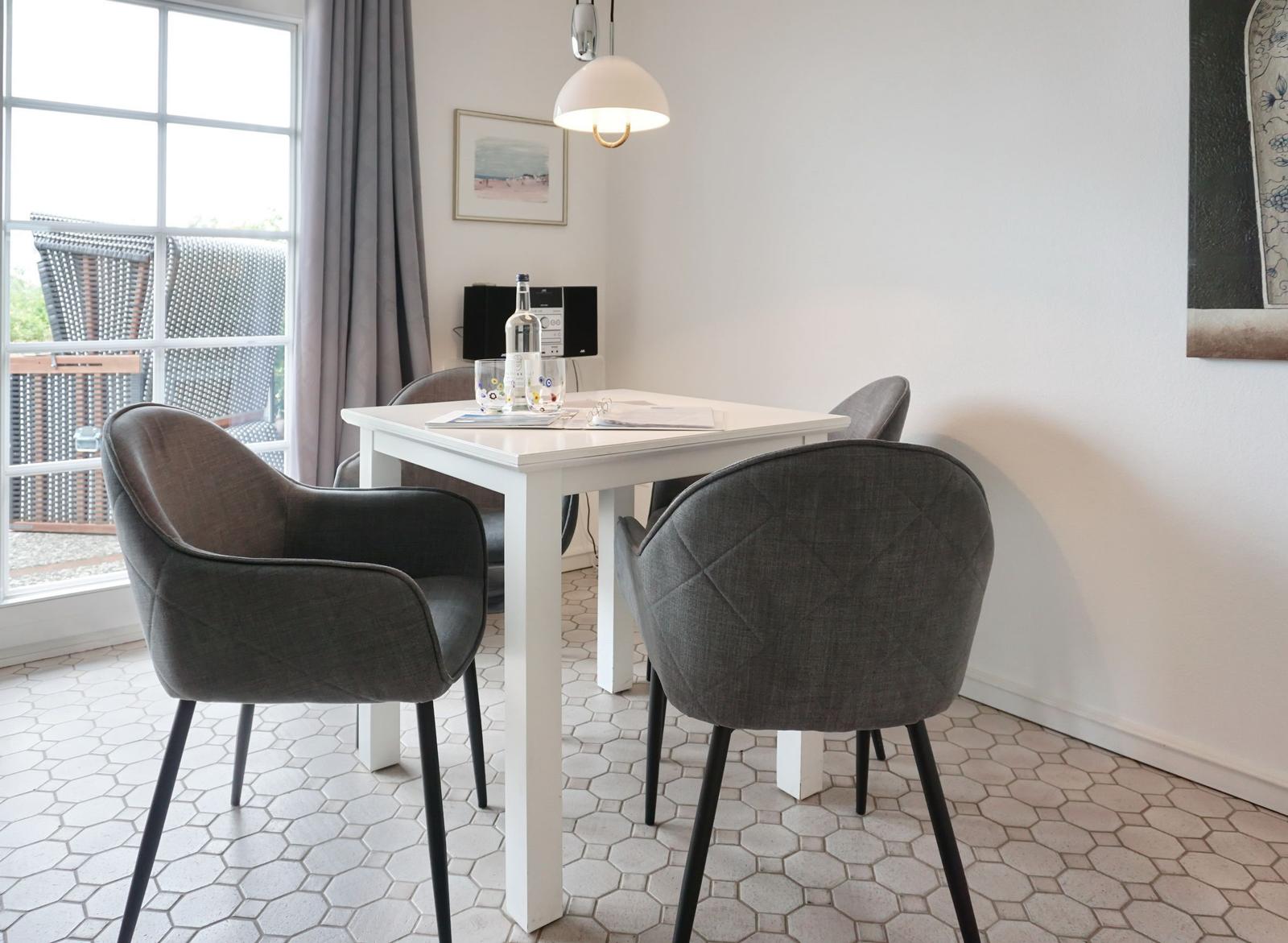 Dining room with white table, four gray chairs, and window to terrace.