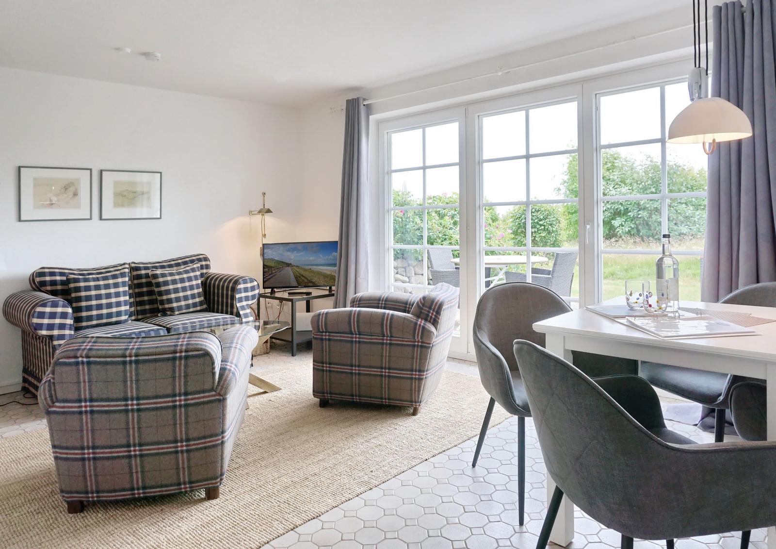 Living and dining area with plaid sofa, dining table, and garden view.