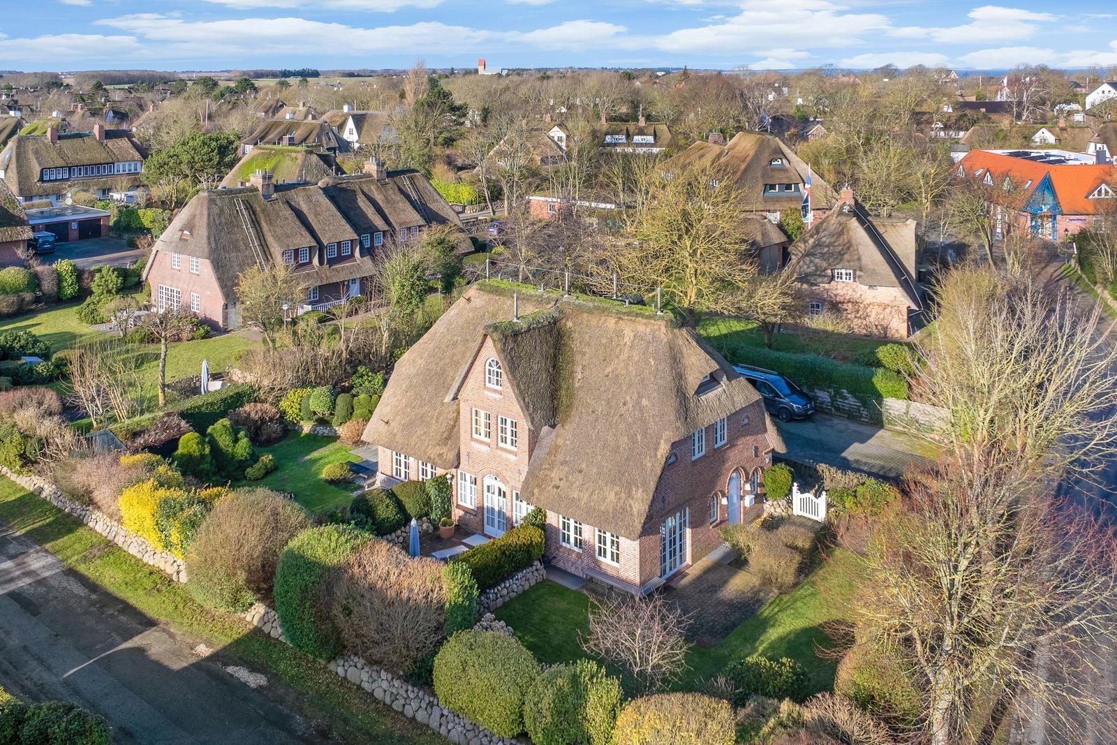Traditional thatched house with garden and surrounding homes