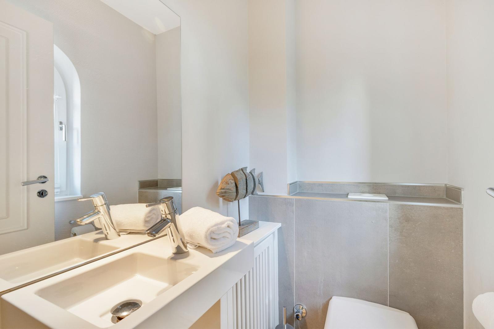 Bathroom with sink, mirror, and toilet. Decorative piece beside the sink.