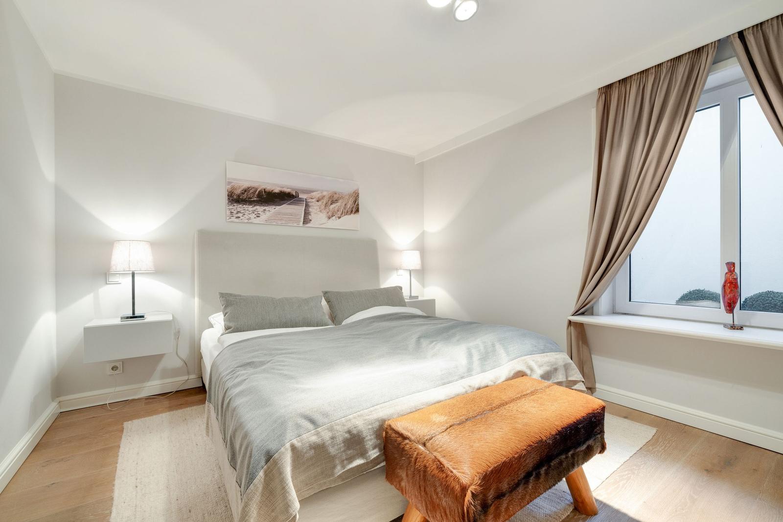 Bedroom with bed, nightstands, and window with curtains.