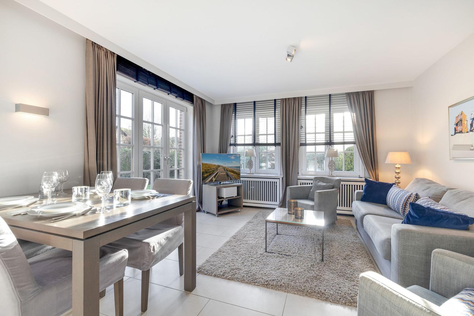 Living and dining area with sofa, table, and windows.