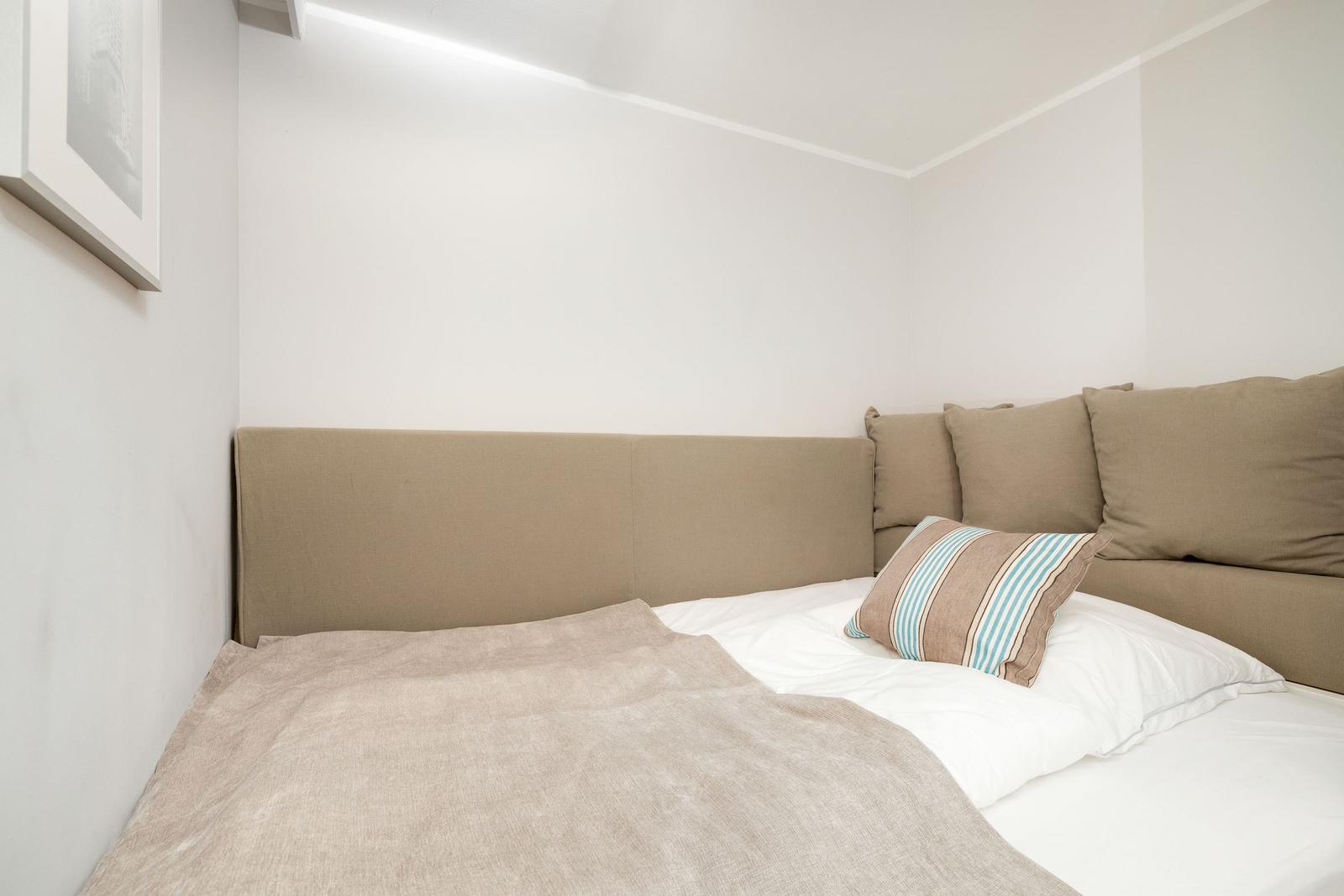 A bed with brown cushions and a striped cushion pillow.