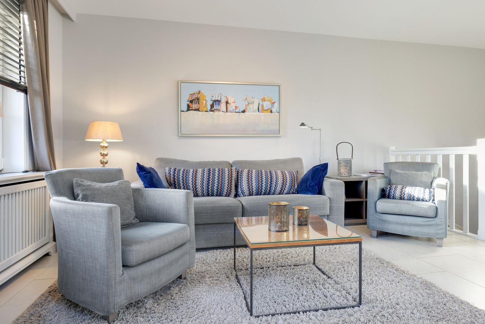 Living room with gray sofa, two armchairs, and glass coffee table.