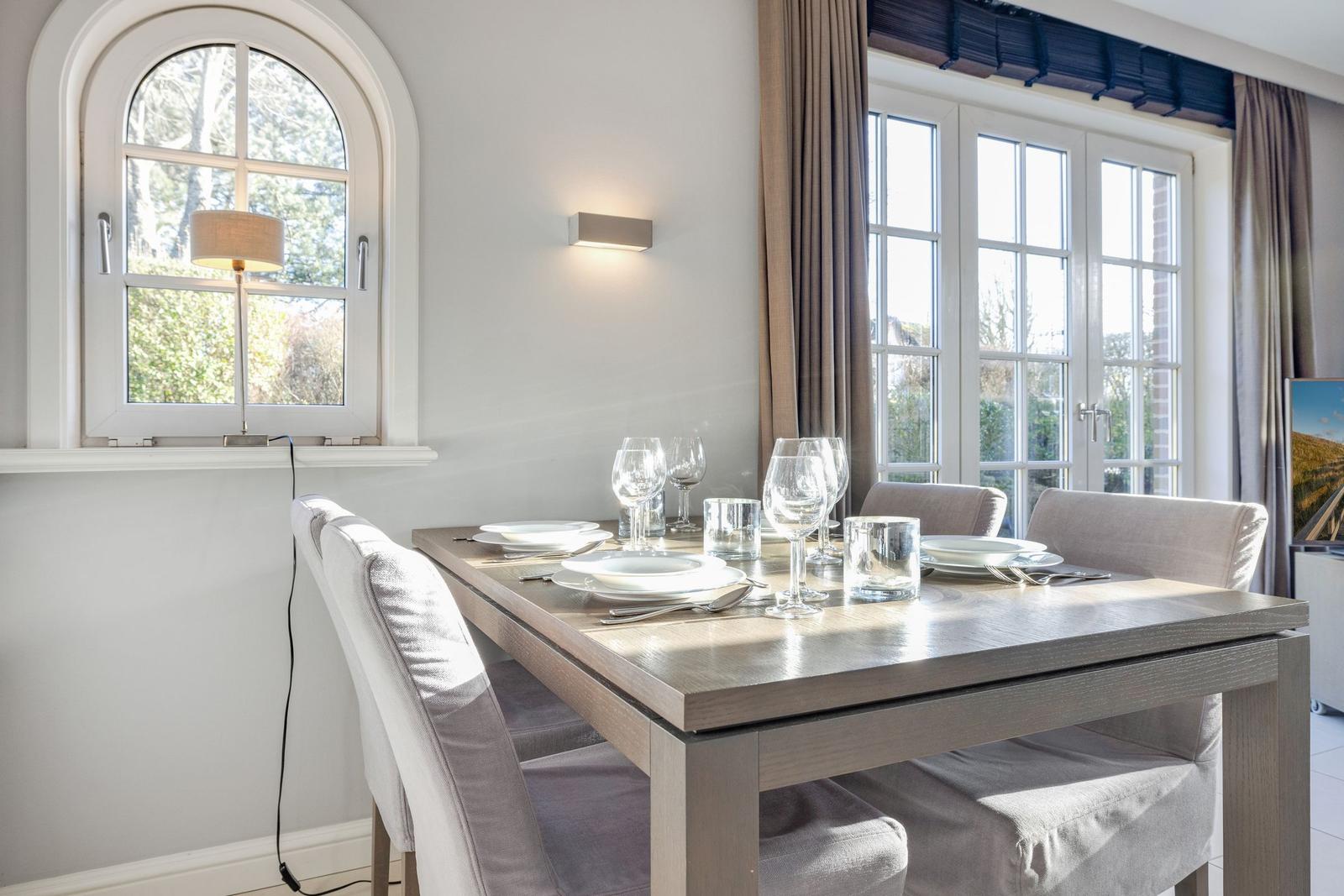 Dining room with table, chairs, and windows.