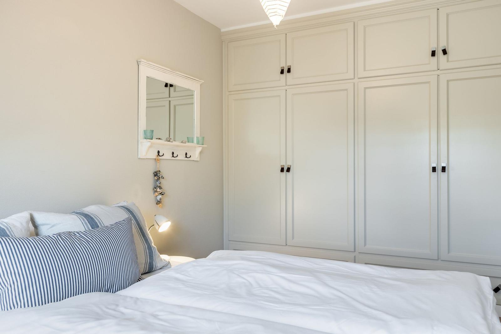 Schlafzimmer mit Bett, Kleiderschrank und Spiegel an der Wand.