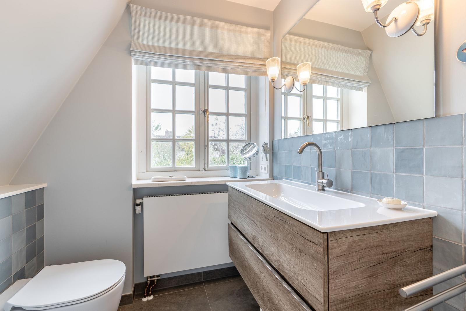 Badezimmer mit Waschbecken, Spiegel und Fenster