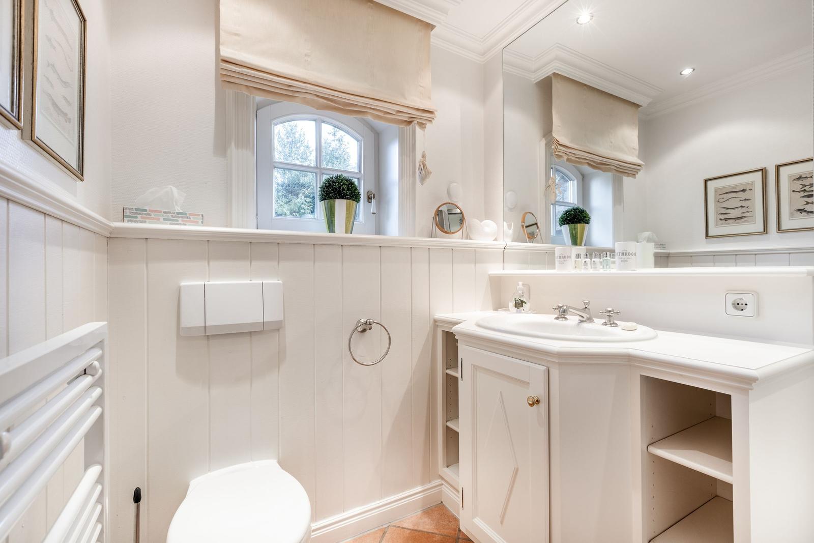 Bathroom with sink, toilet, and window. White fixtures with mirror.