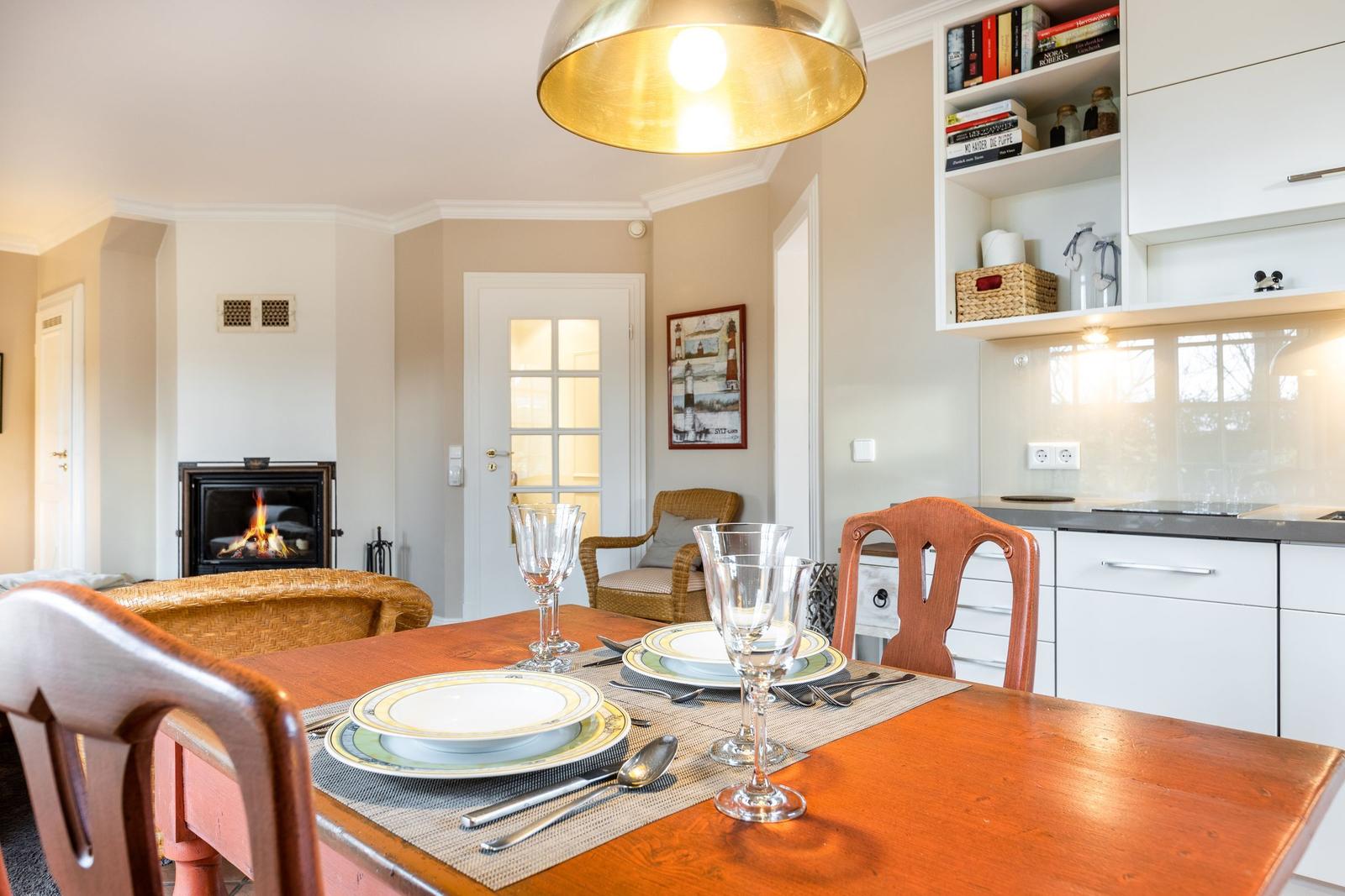 Dining room with table, chairs, and fireplace. Kitchen with white cabinets.
