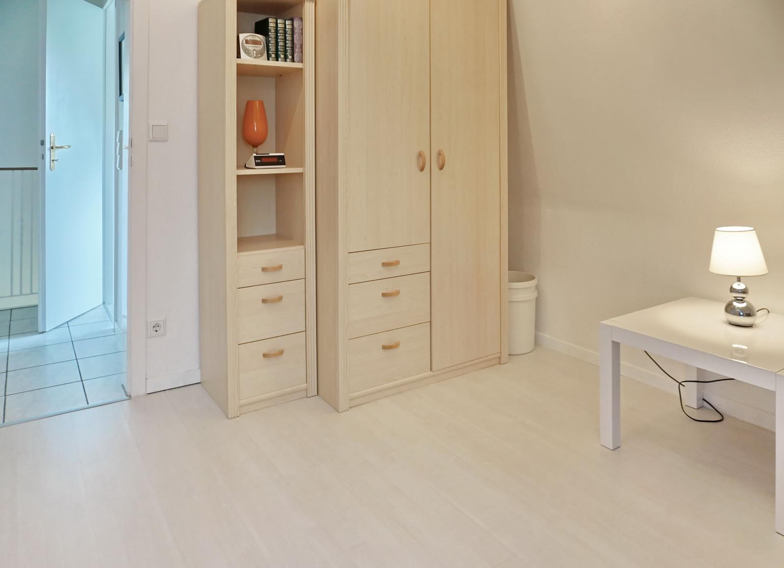 Bedroom with wardrobe, desk, and lamp.