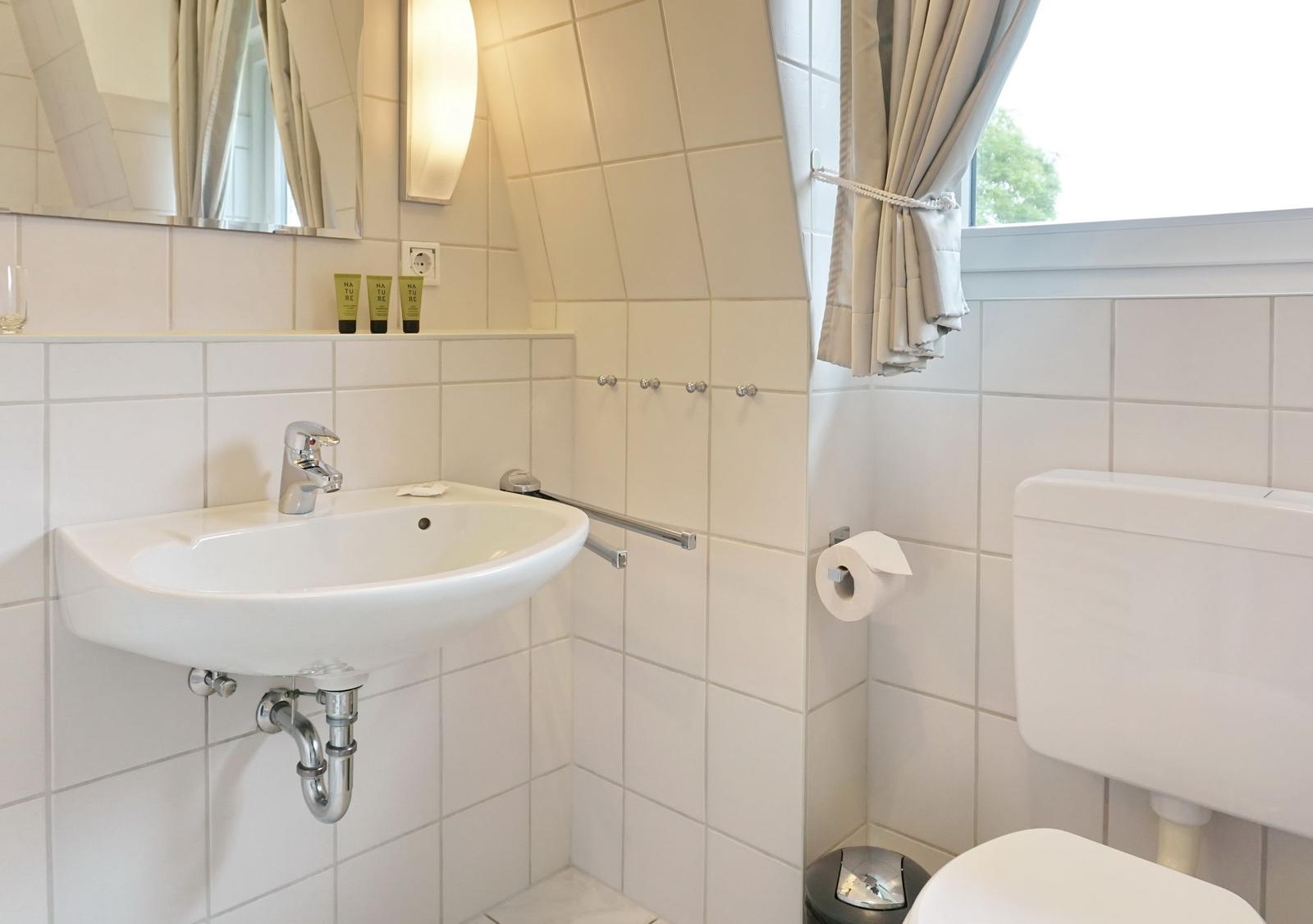 Bathroom with sink, toilet, and window.