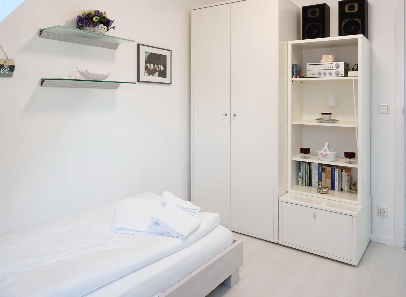 Bedroom with bed, wardrobe, and bookshelf.