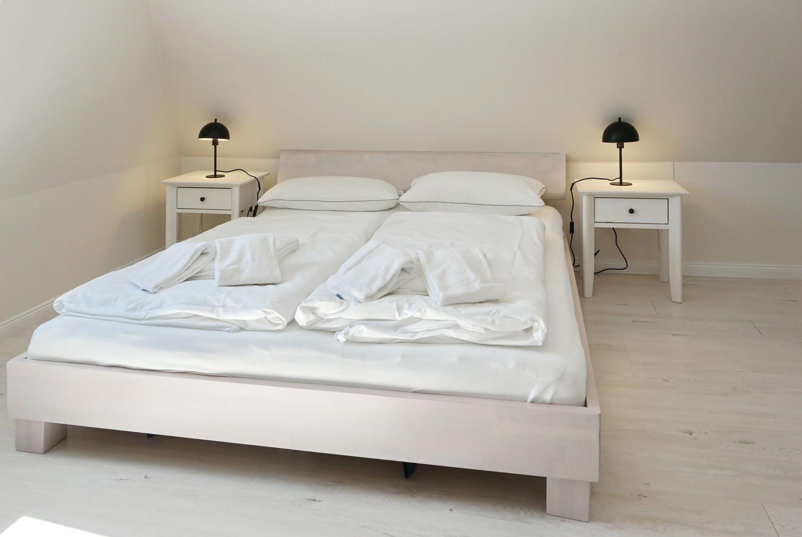 Bedroom with white bed, two nightstands, and black lamps.