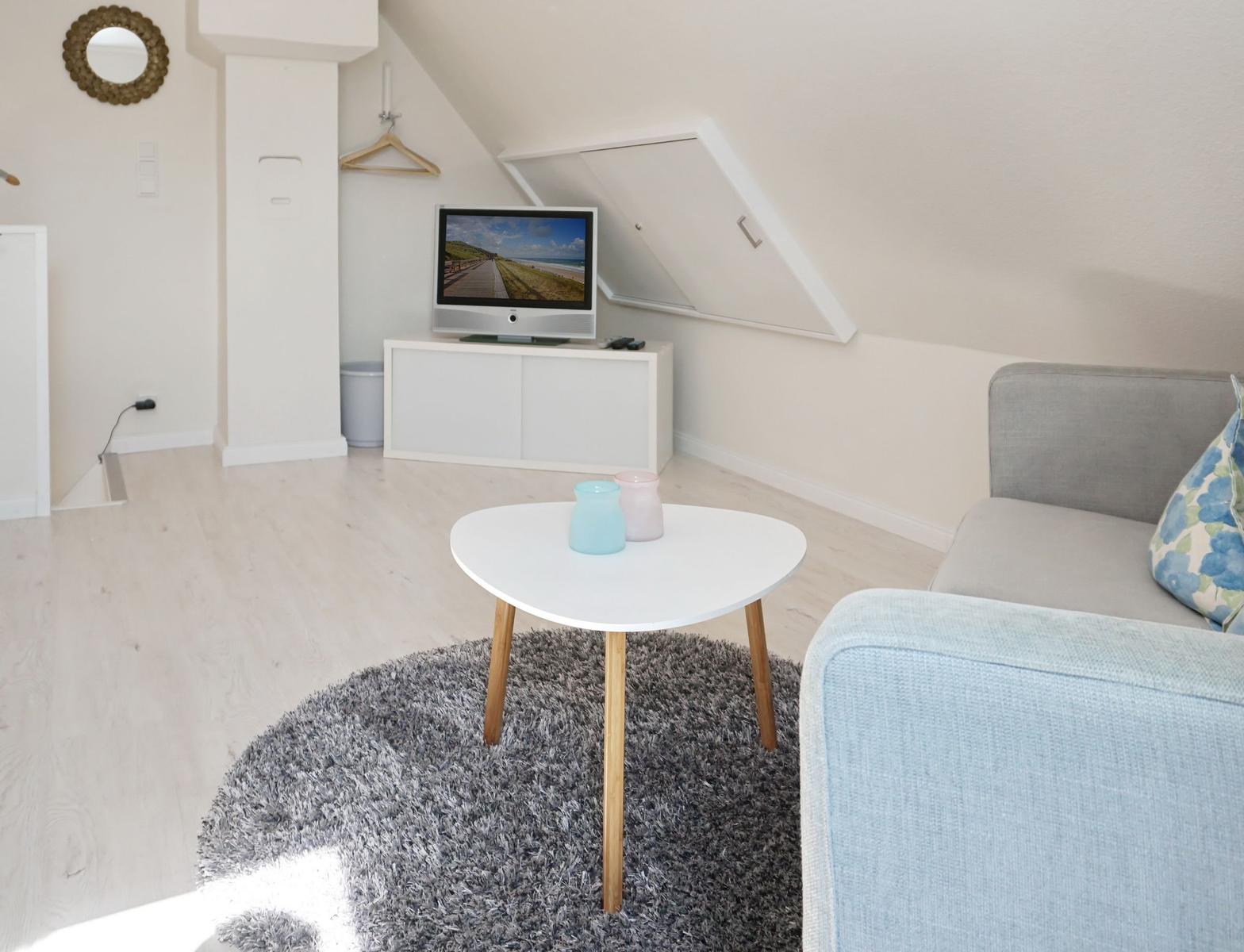 Living room with sofa, table, and TV under sloped ceiling