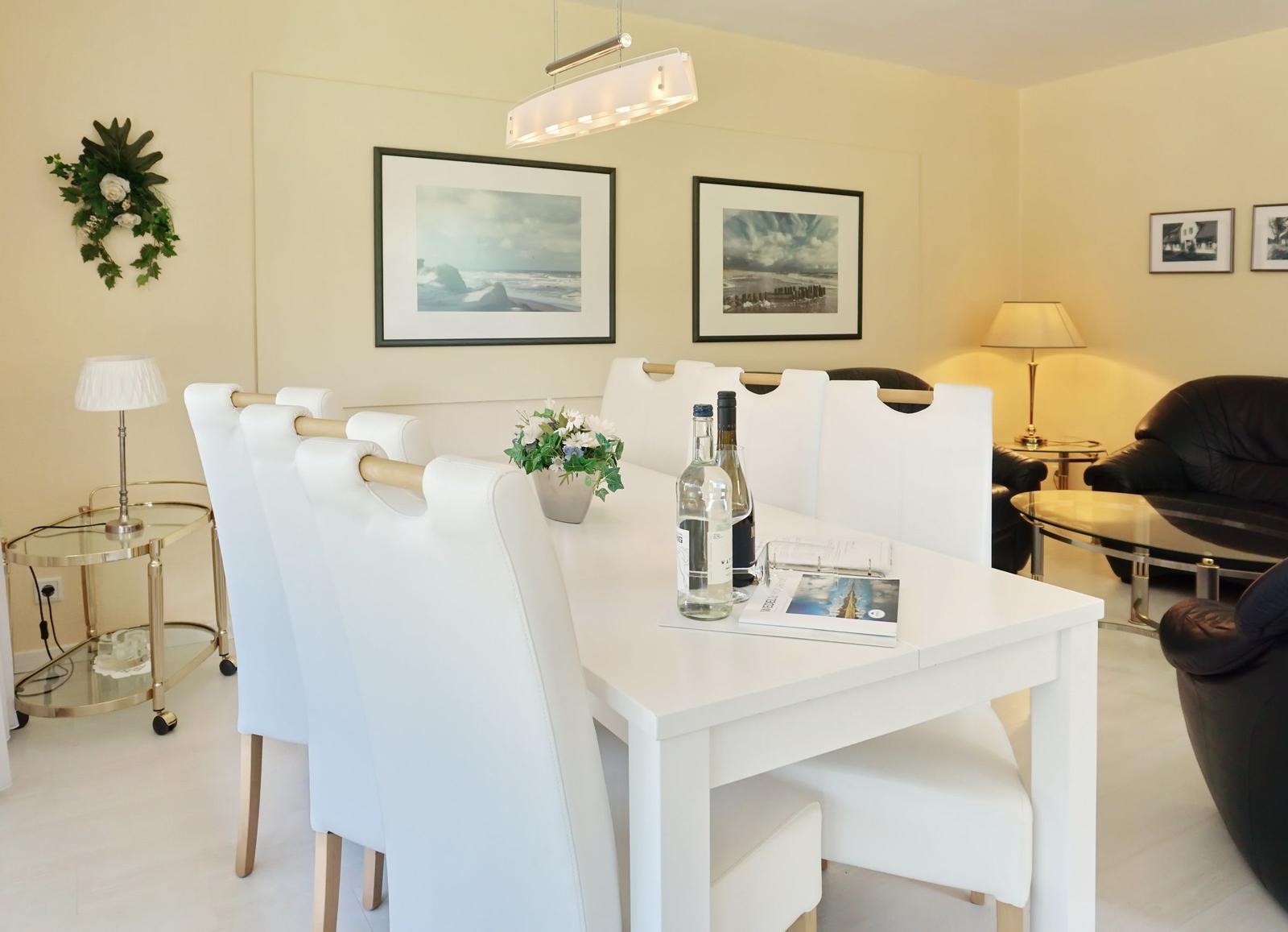 Dining area with white table and chairs, wall art and lamp
