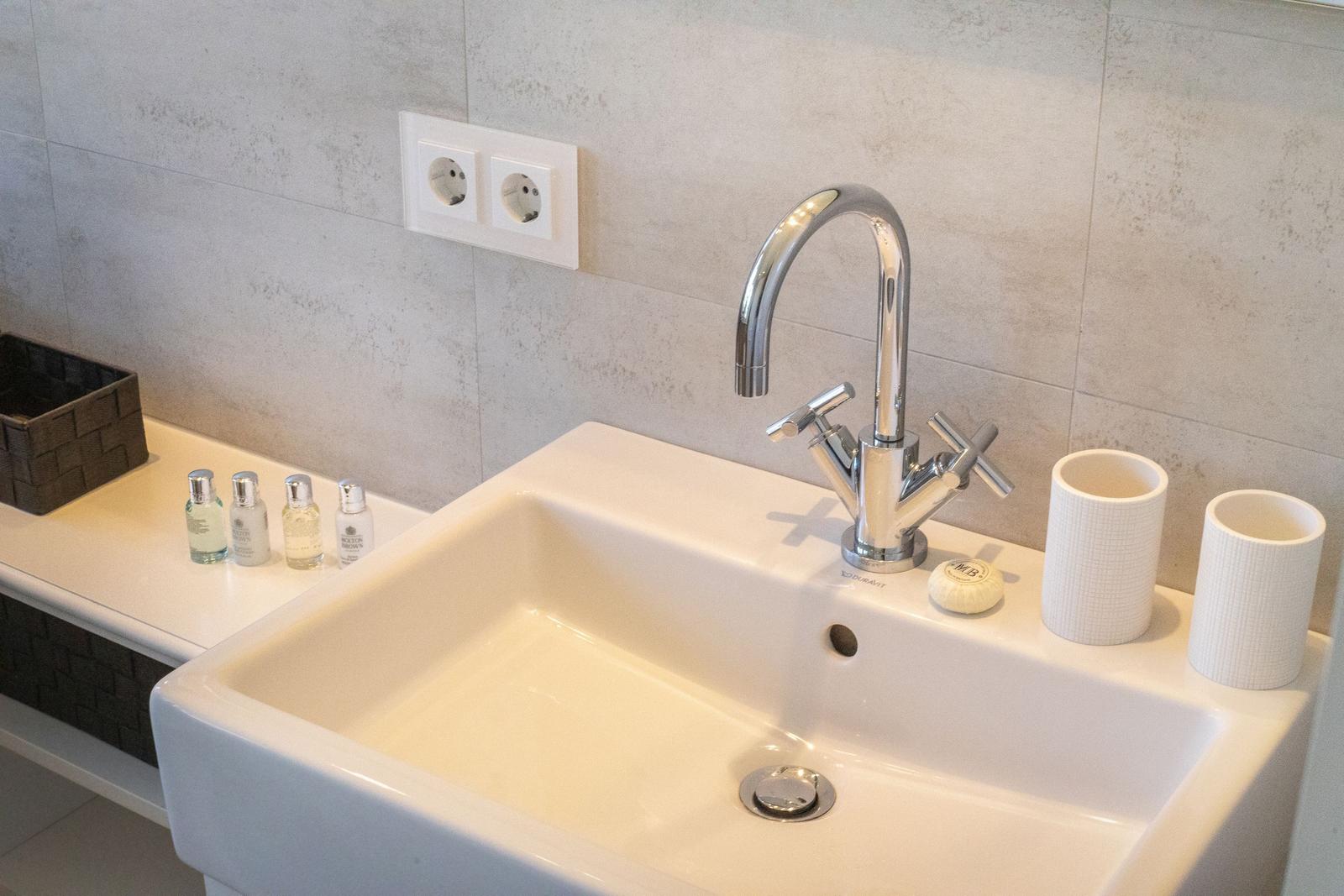 Waschbecken mit Armatur und Flaschen auf Ablagefläche