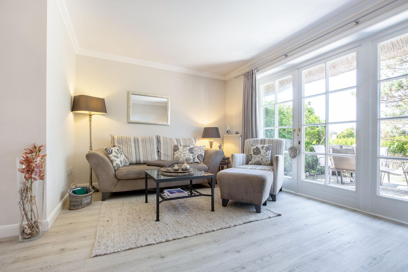 Wohnzimmer mit Sofa, Sessel und Glastür zur Terrasse