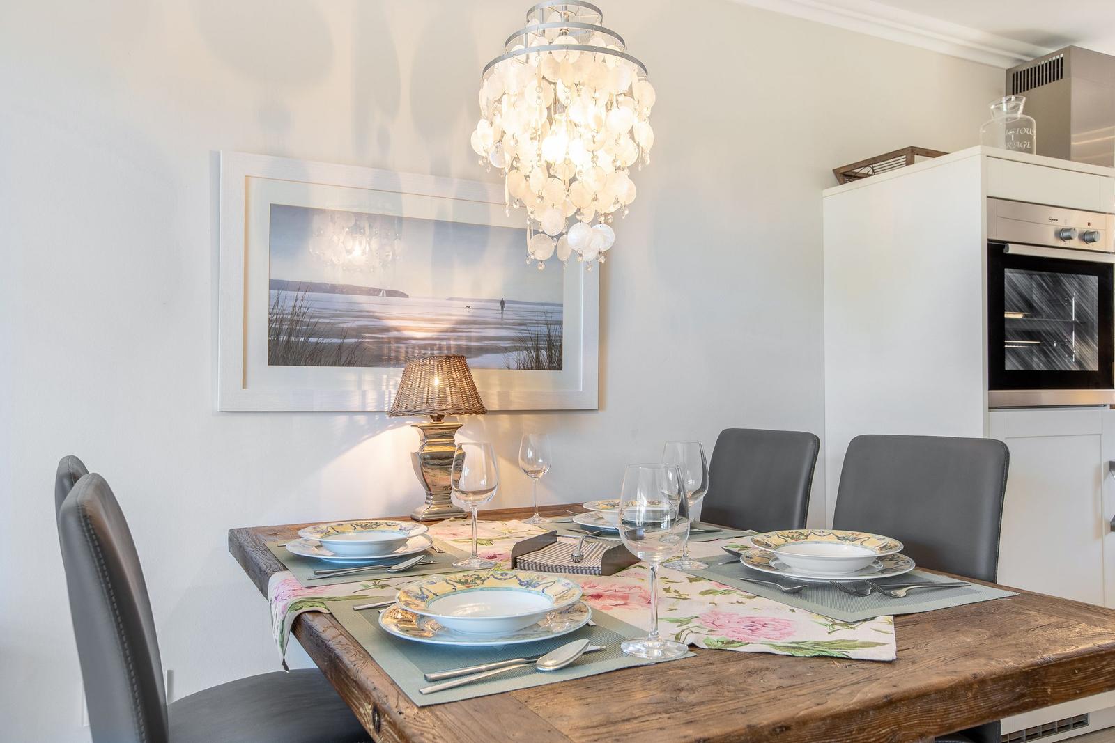 Esszimmer mit rustikalem Tisch, grauen Stühlen und moderner Deckenleuchte.