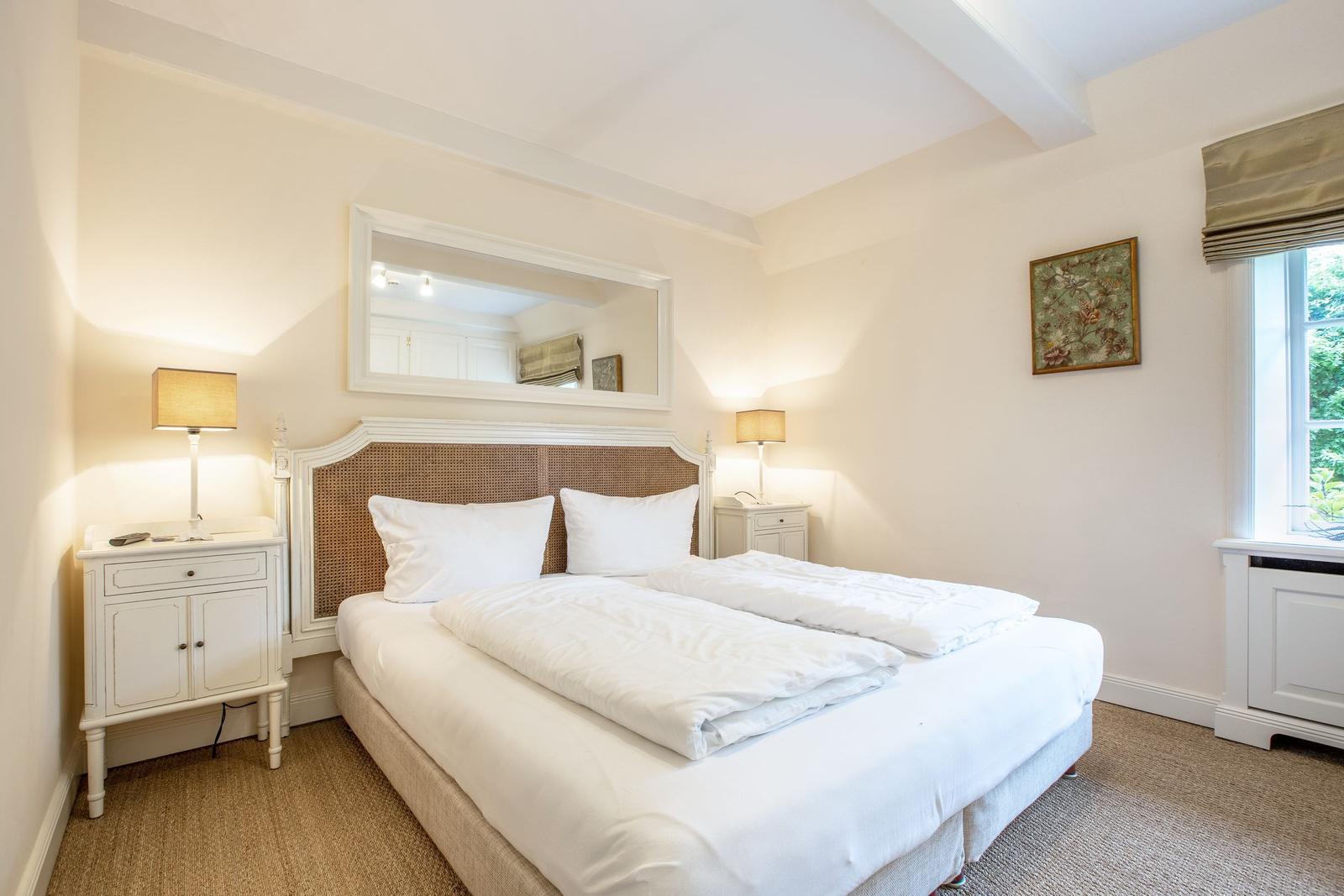 Bedroom with double bed, nightstands, and mirror on the wall.