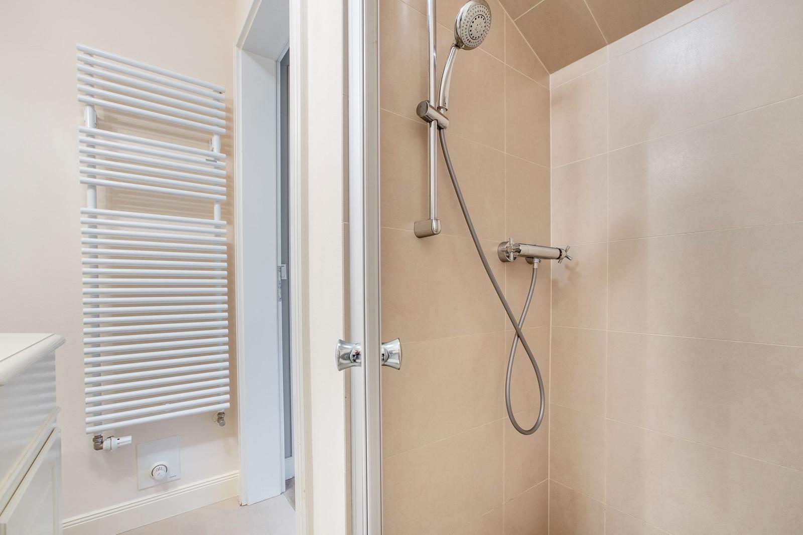 Shower cabin with handheld shower and wall-mounted heater